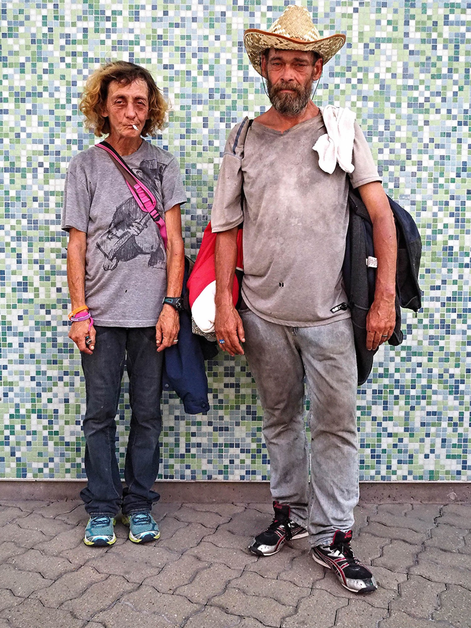 Photograph by Tom TBow Bowden of an old couple sweaty from walking and standing by a mosaic war