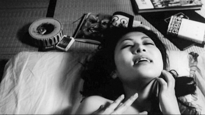 A black-and-white photos of a woman lying on her back with eyes closed touching her neck