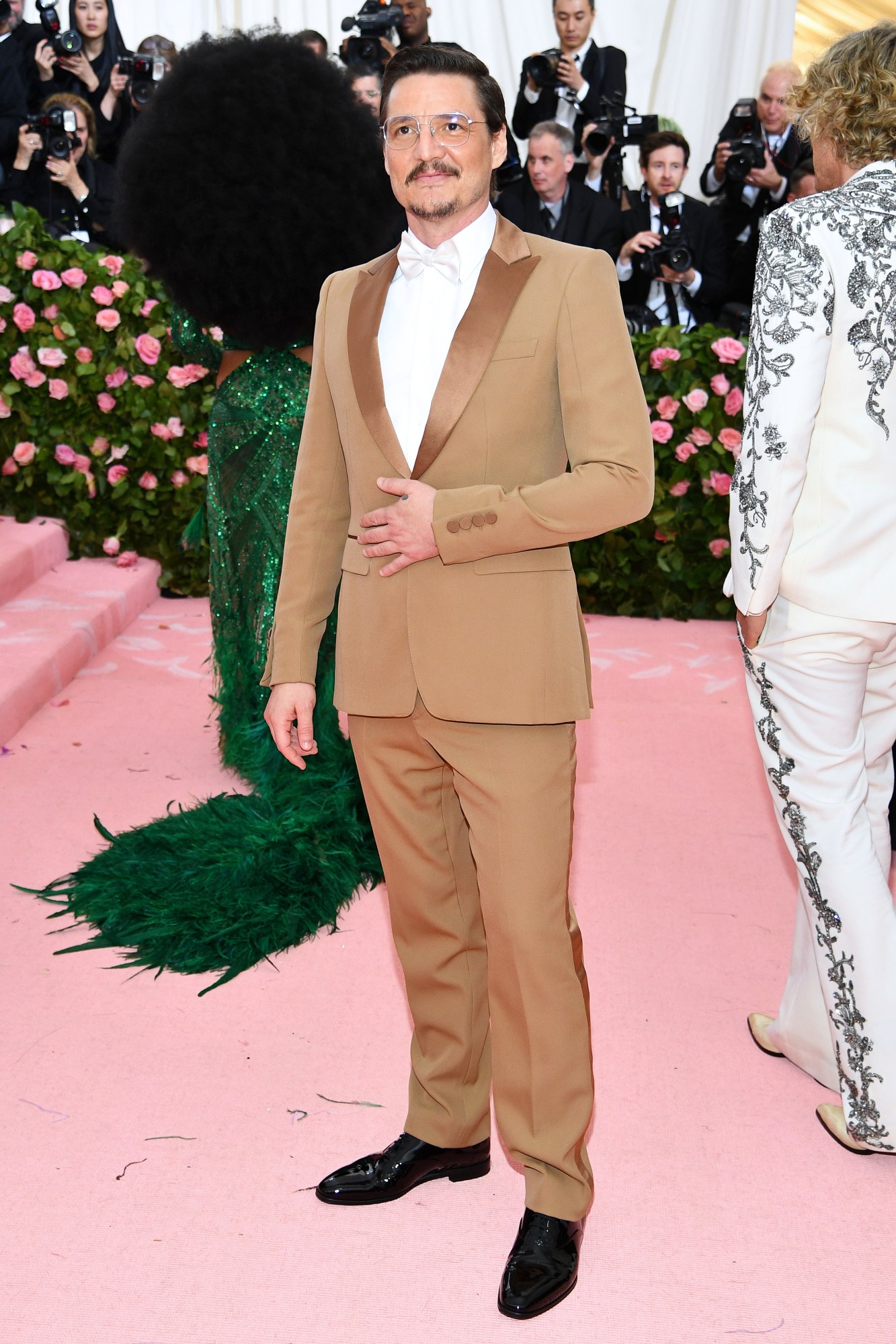 Pedro Pascal walks a pink carpet wearing a brown gucci suit at the Met Gala 2019 themed Camp