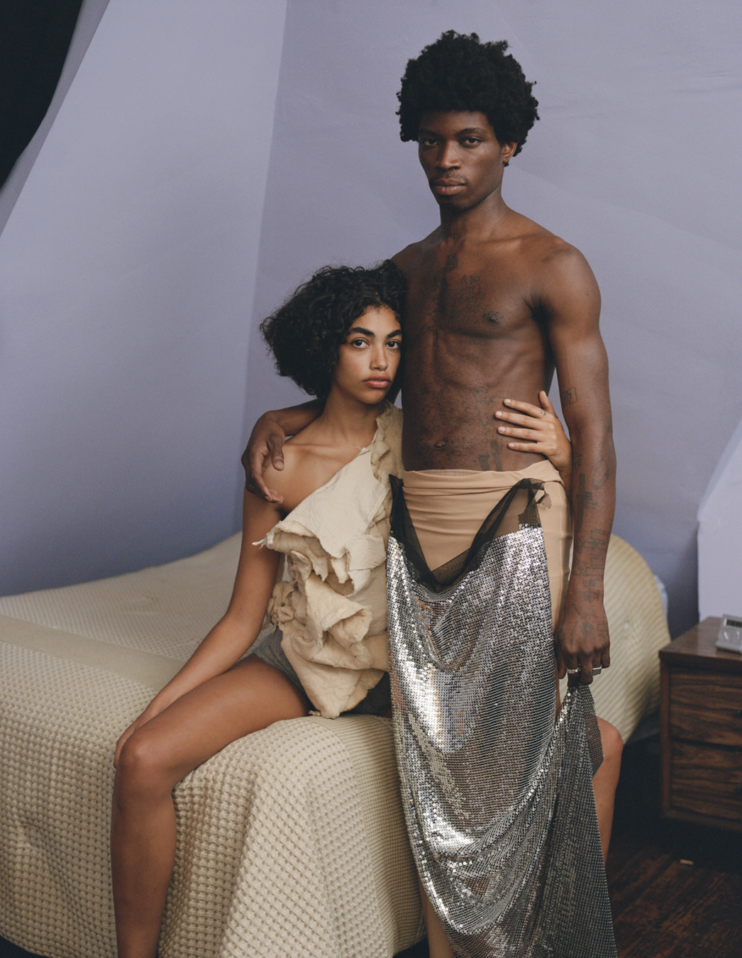 Two models sat or standing by a bed wears clothes by Ponte in a photograph by Deirdre Lewis in i-D’s The Timeless Issue, no. 371, Spring 2023