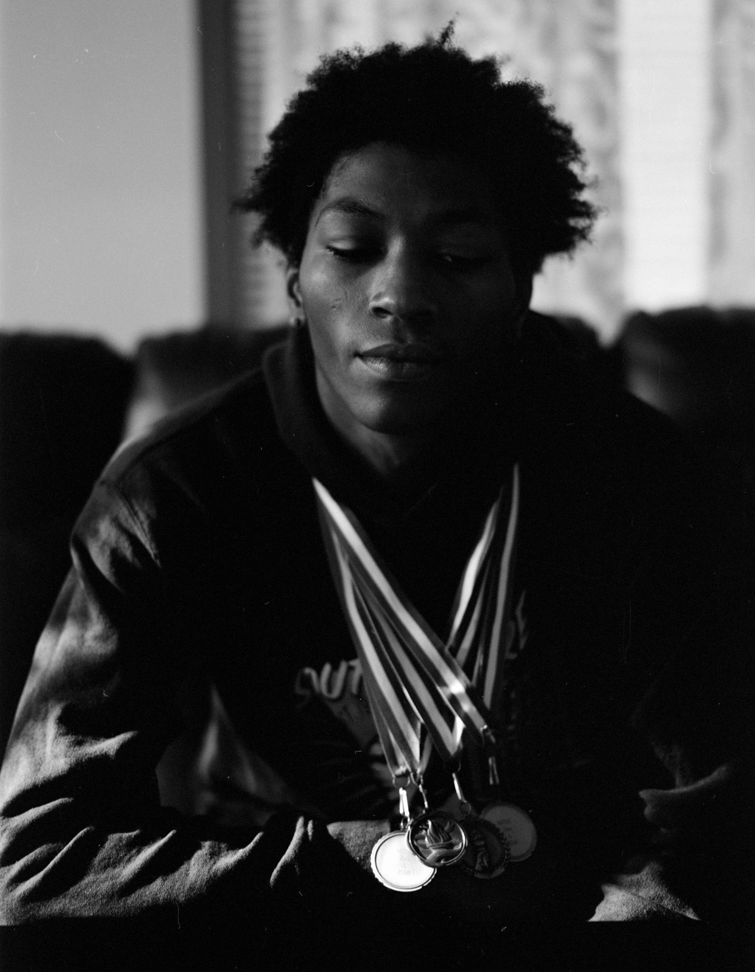 Black-and-white photo of a member of Chicago's South Shore Drill Team displaying their medals