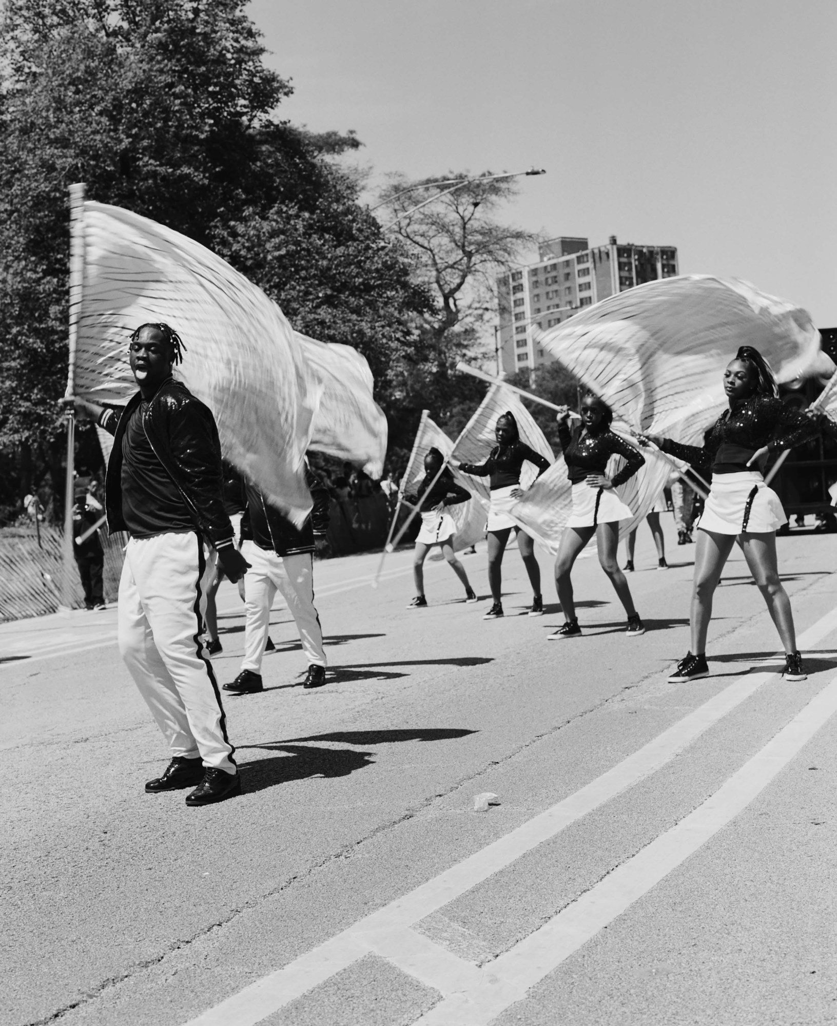 Black-and-white photo of Chicago's South Shore Drill Team twirling flags as part of a procession