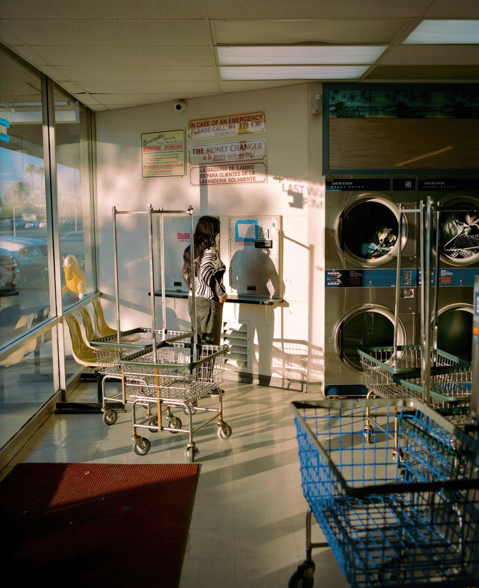 a woman standing in a laundromat with light steaming in