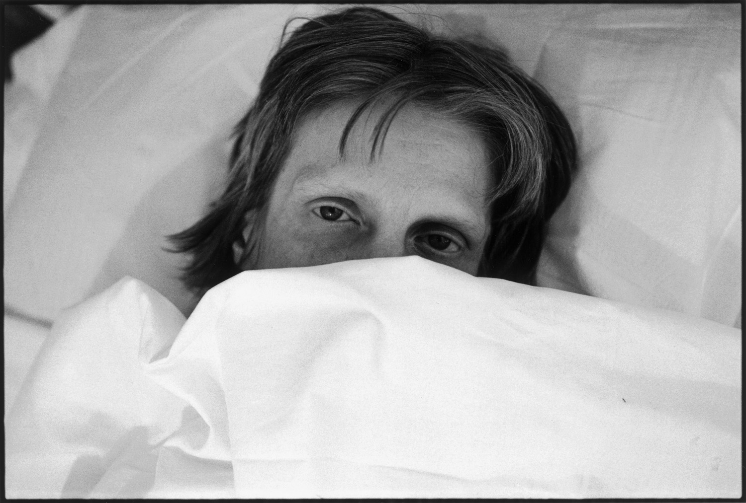 A woman posing for a portrait while lying in bed