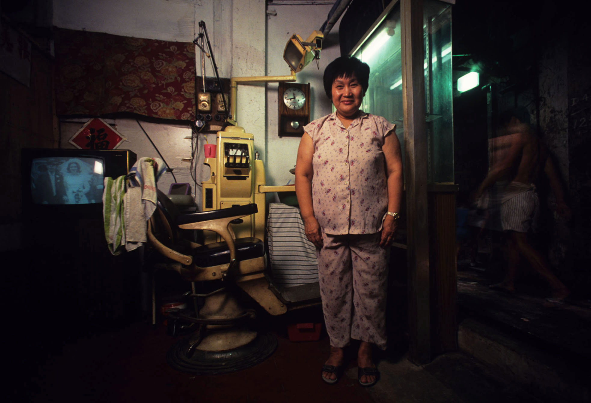 A woman poses in her pyjamas in her home within Kowloon Walled City