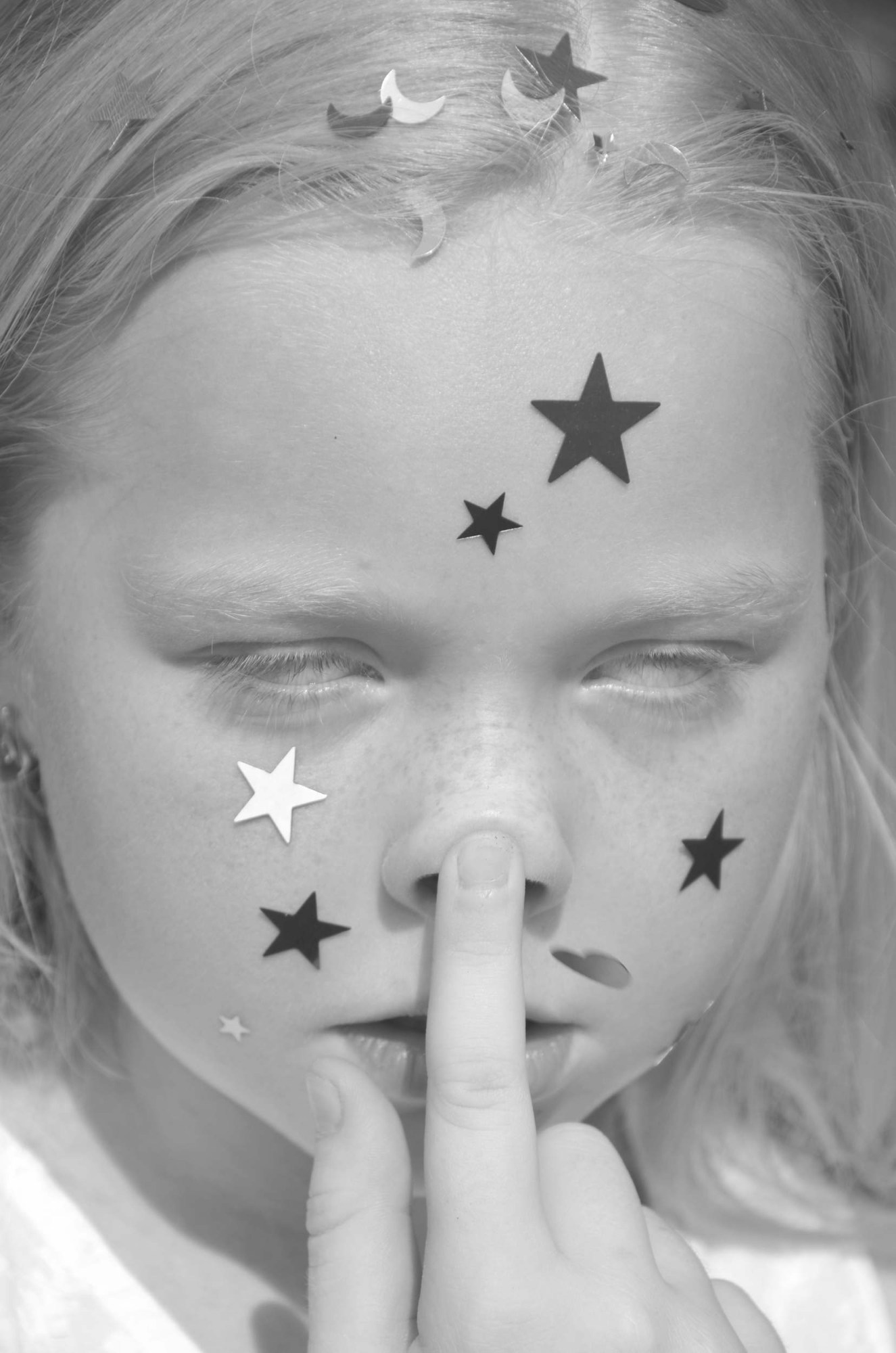 a young girl with star stickers on her face pushes her nose up like a pig and rolls her eyes back