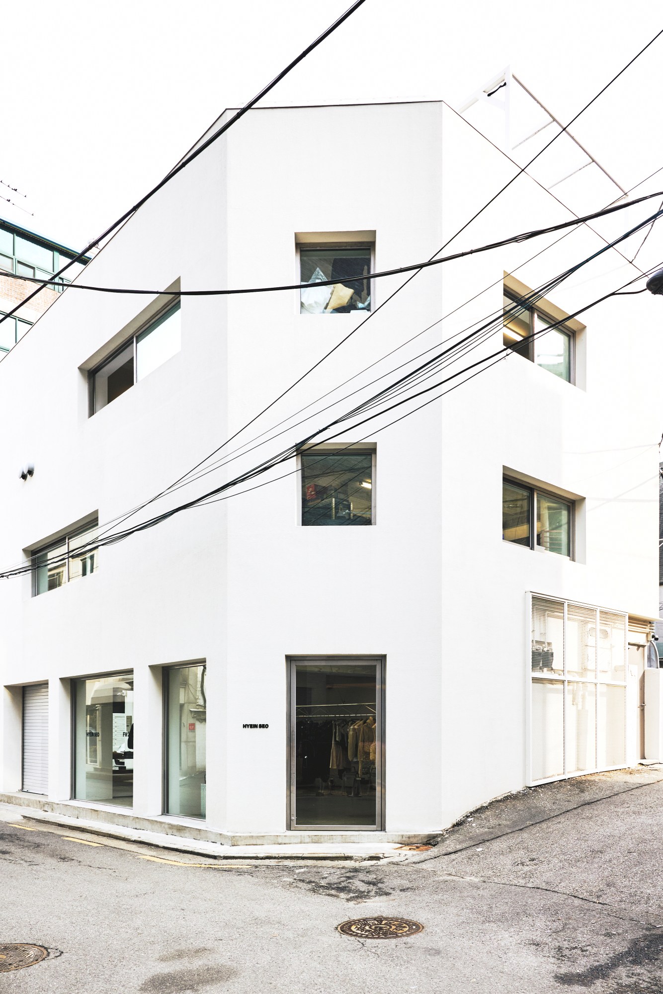 a three-story building with large windows on the corner of a street in seoul