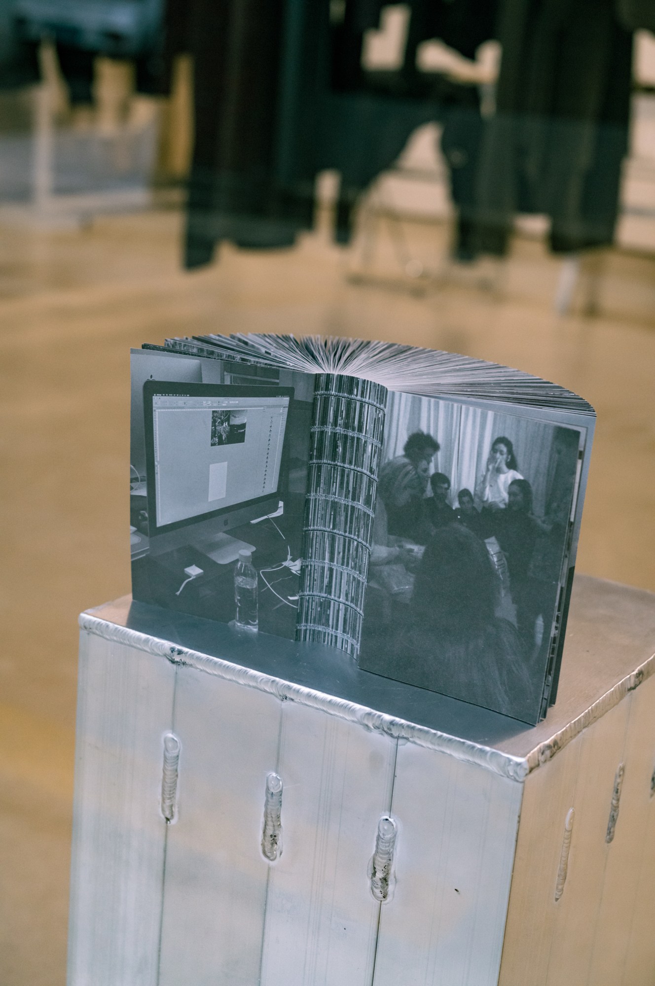 a book of black and white photographs is splayed open on a silver plinth