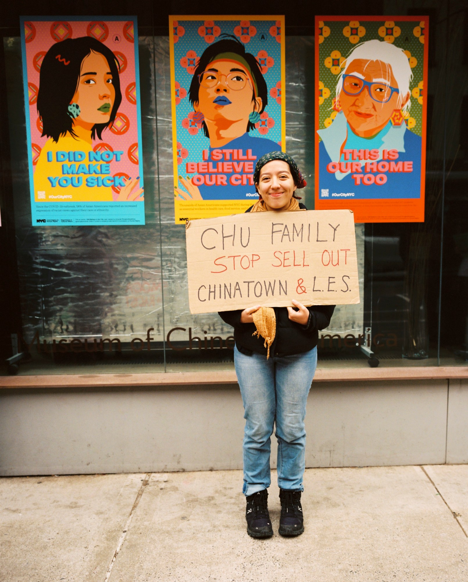 jihye song holding a cardboard protest sign and posing in new york's chinatown