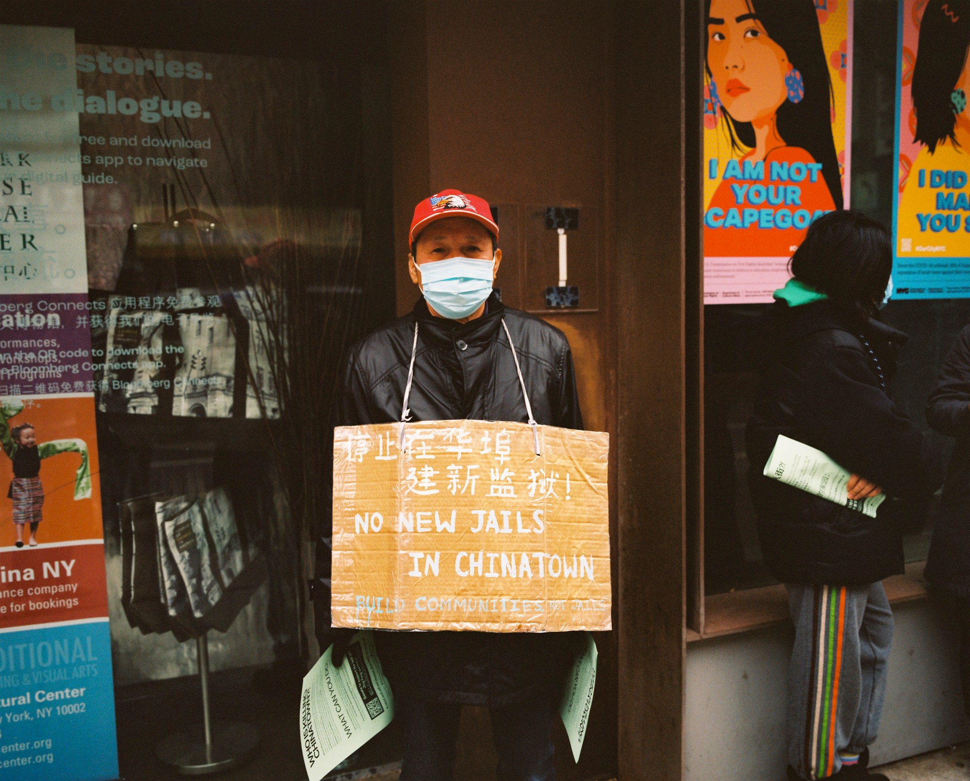 an old man with a sign that reads no new jails in chinatown