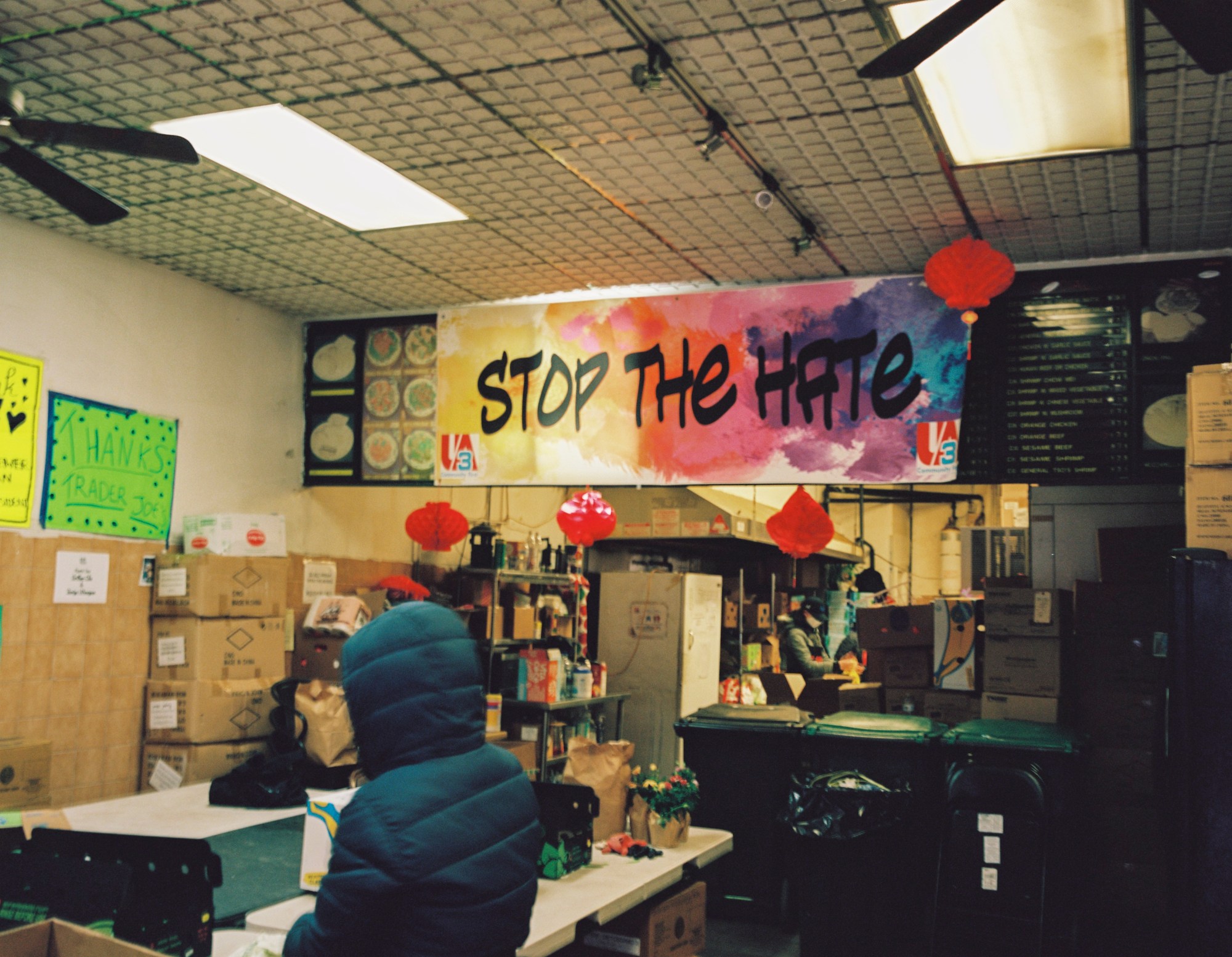 a large stop the hate sign taped up over a restaurant menu in chinatown