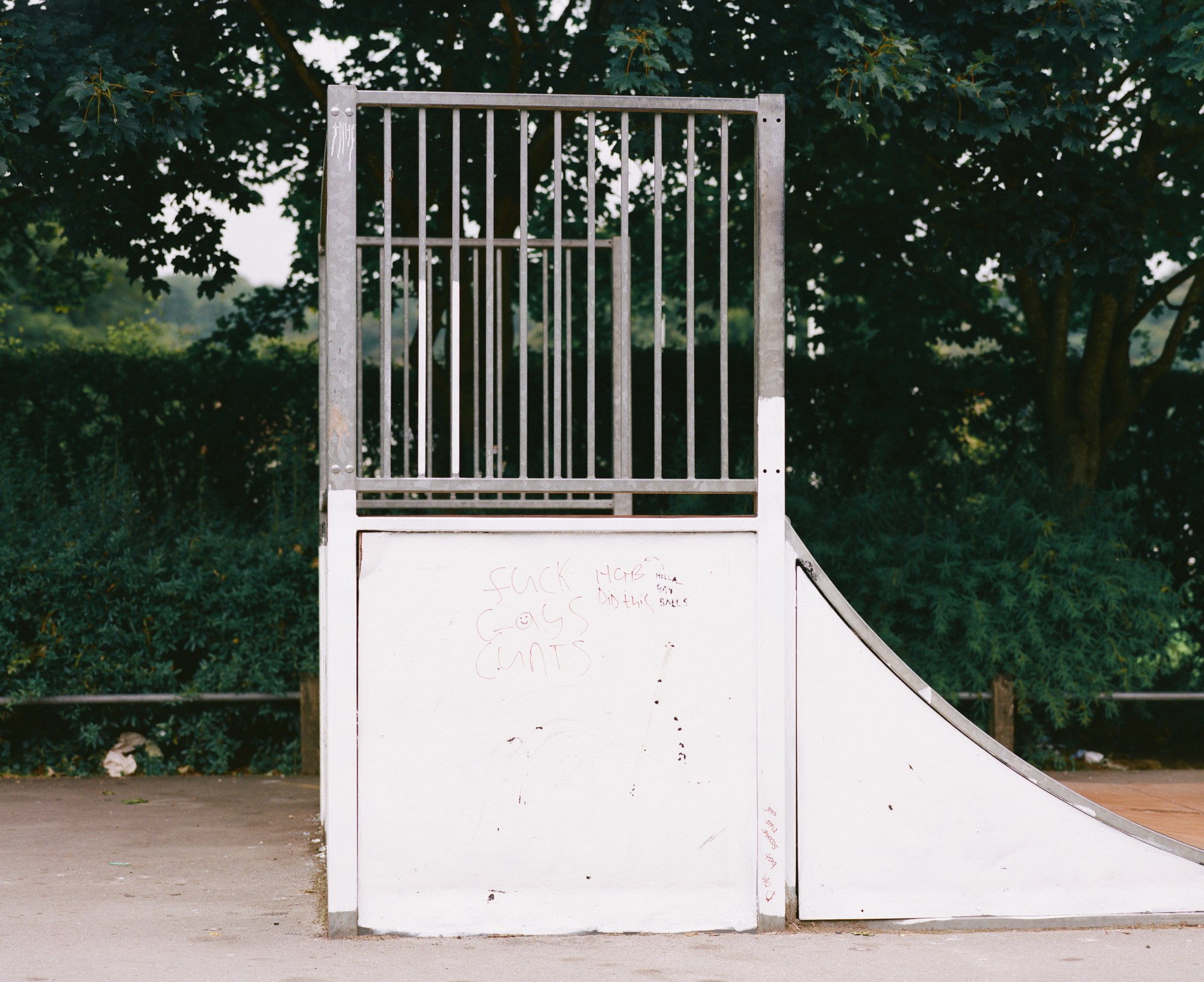 a halfpipe in a skate park, with the words FUCK GAYS CUNTS graffitied onto the side