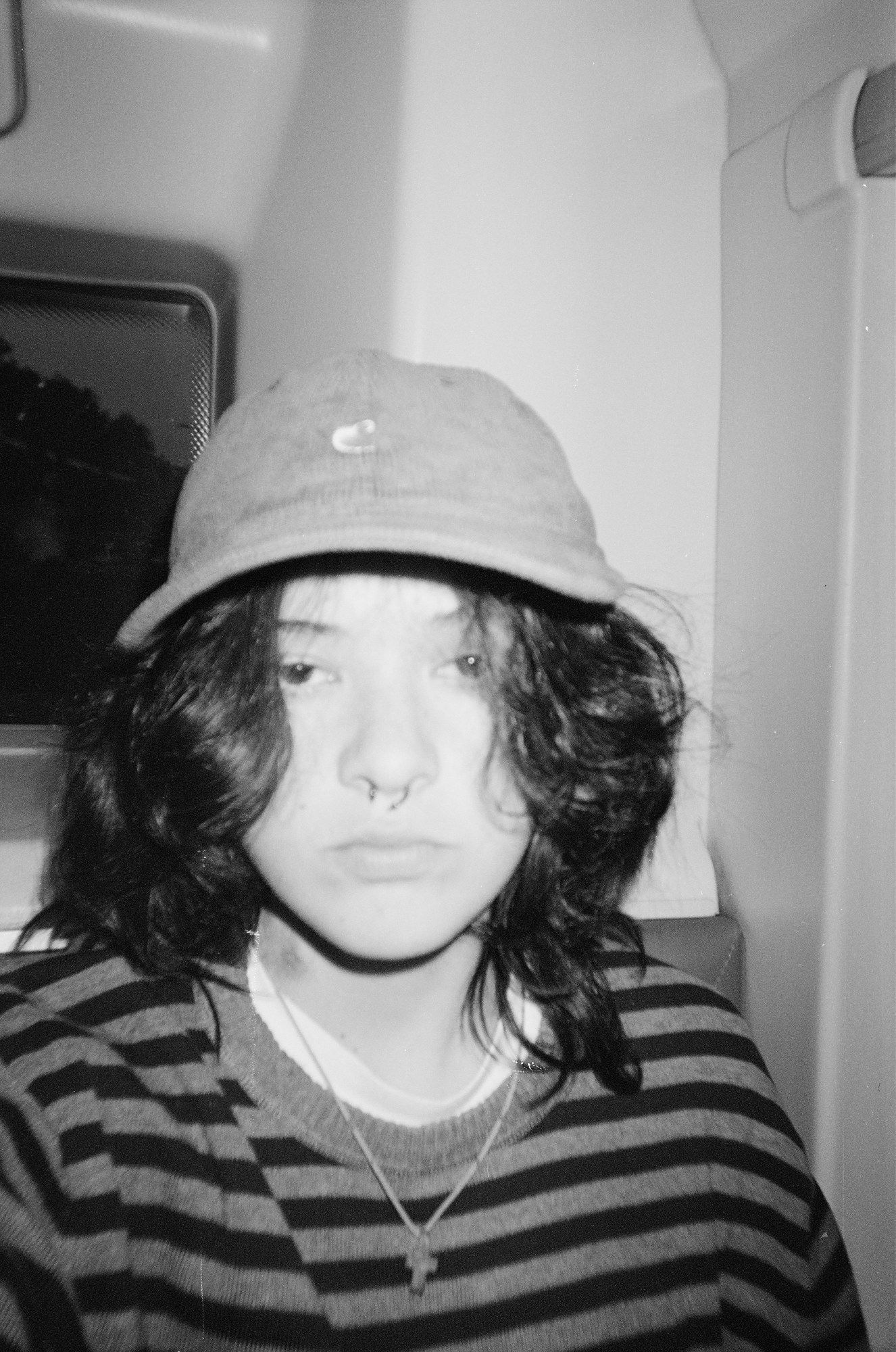 a person in a striped jumper with dyed dark hair and a septum piercing in black and white