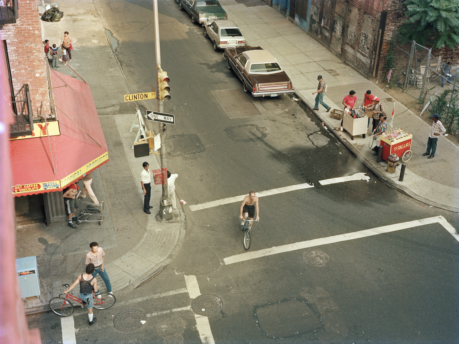 a view from an upstairs window of pushcart sellers and people in the street