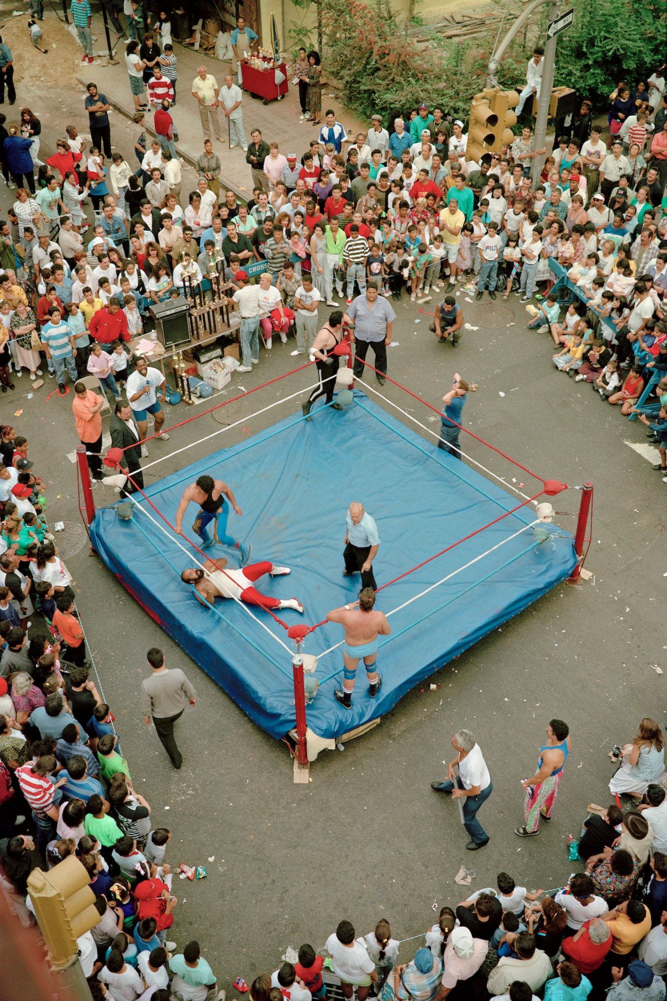 a wrestling ring on a street corner is surrounded by crowds of people