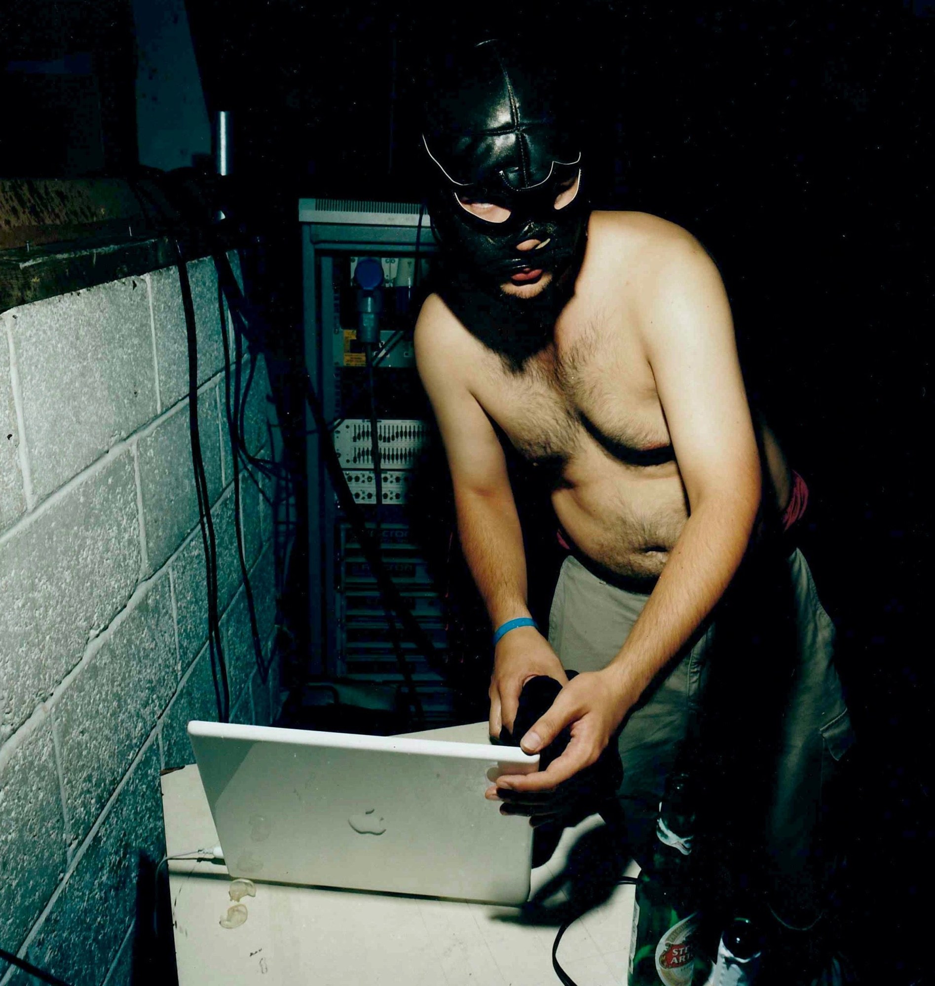 A topless man in a wrestling mask uses a white iMac