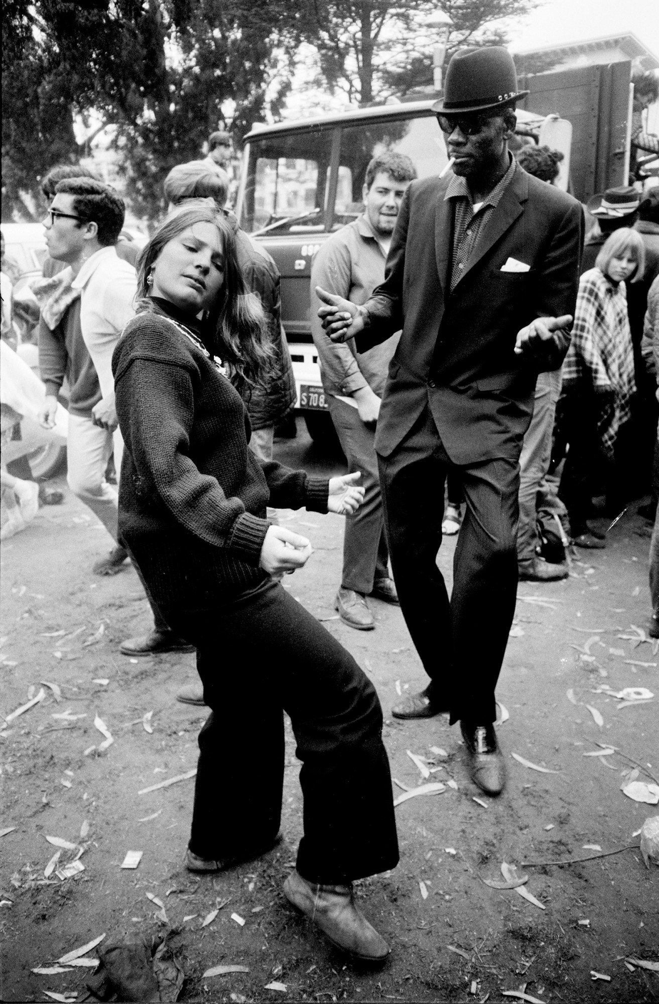 Black-and-white photograph by Steve Schapiro from 1967 of a group of hippies dancing outside in San Francisco.