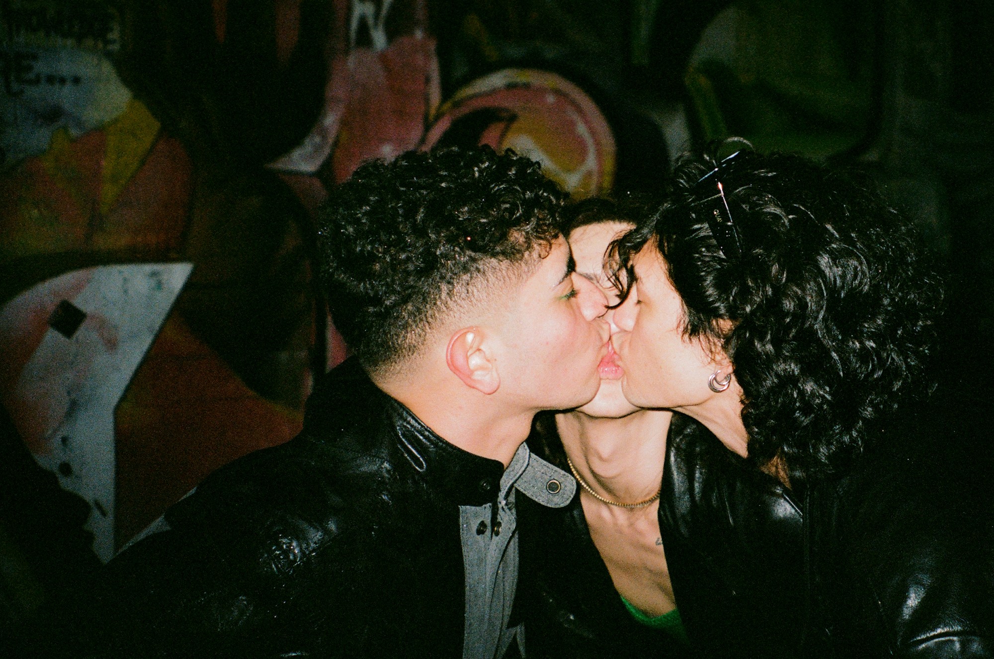 three people kissing at a party in new york