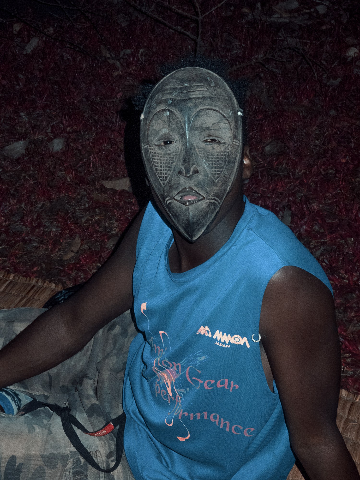 A man wearing a metal face mask and blue sleeveless top with camo trousers