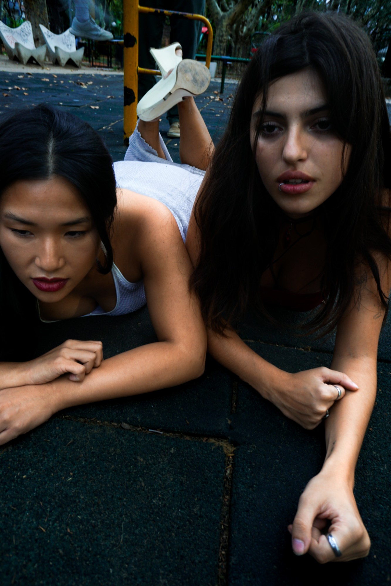 Two girls lying on their fronts in a play park