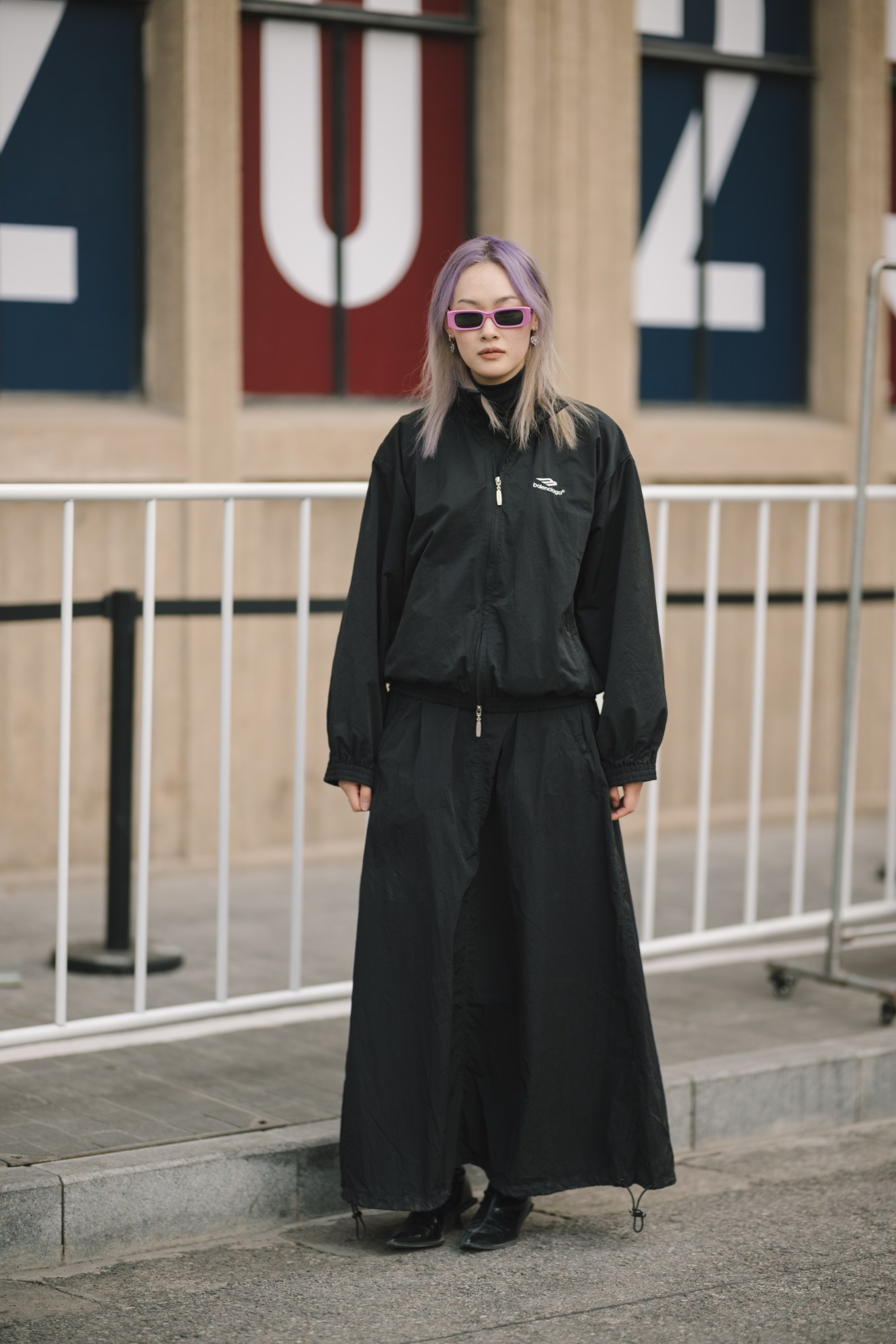 a model in oversized black streetwear and purple hair looks to camera