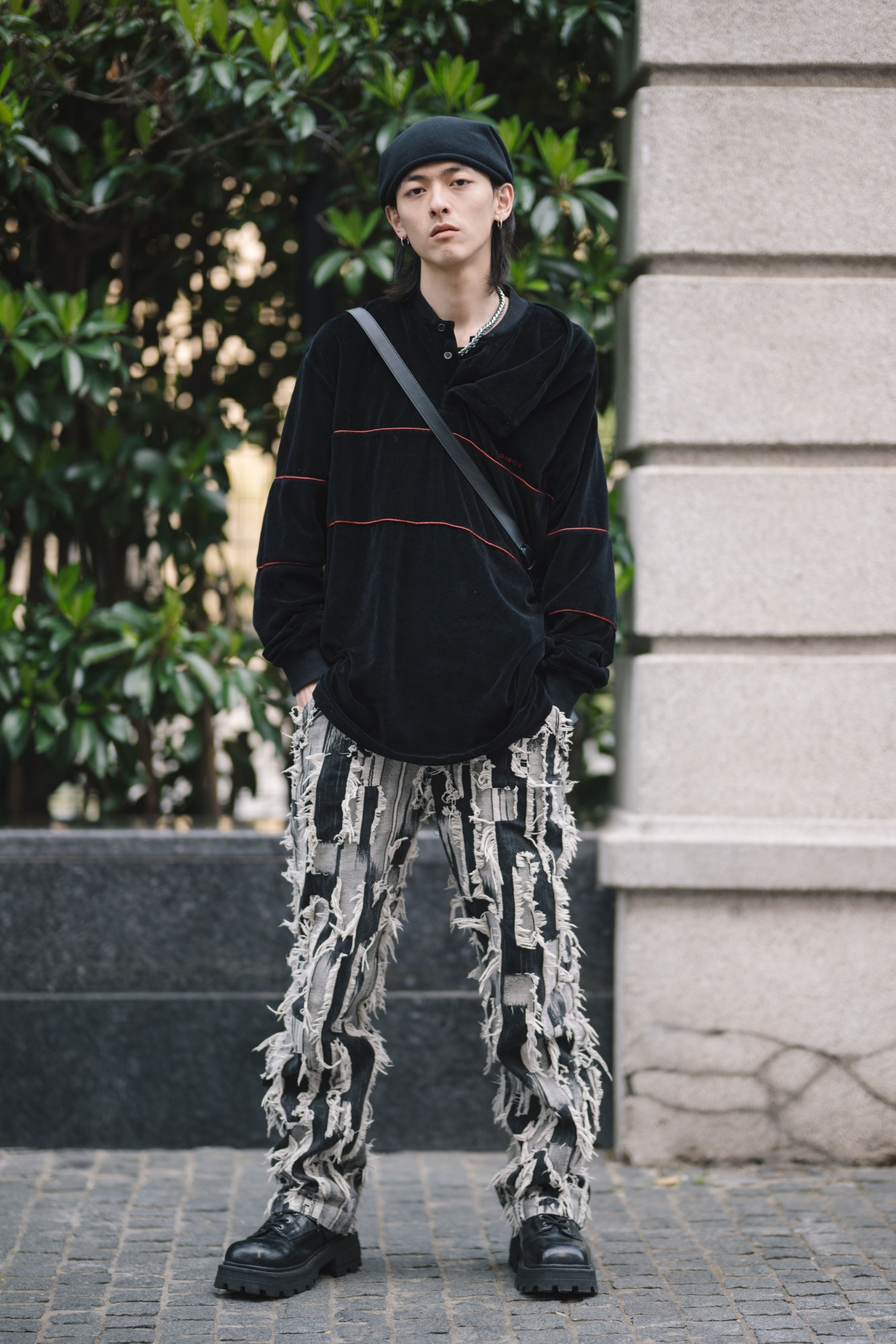 a model in distressed jeans and heavy boots poses in the street