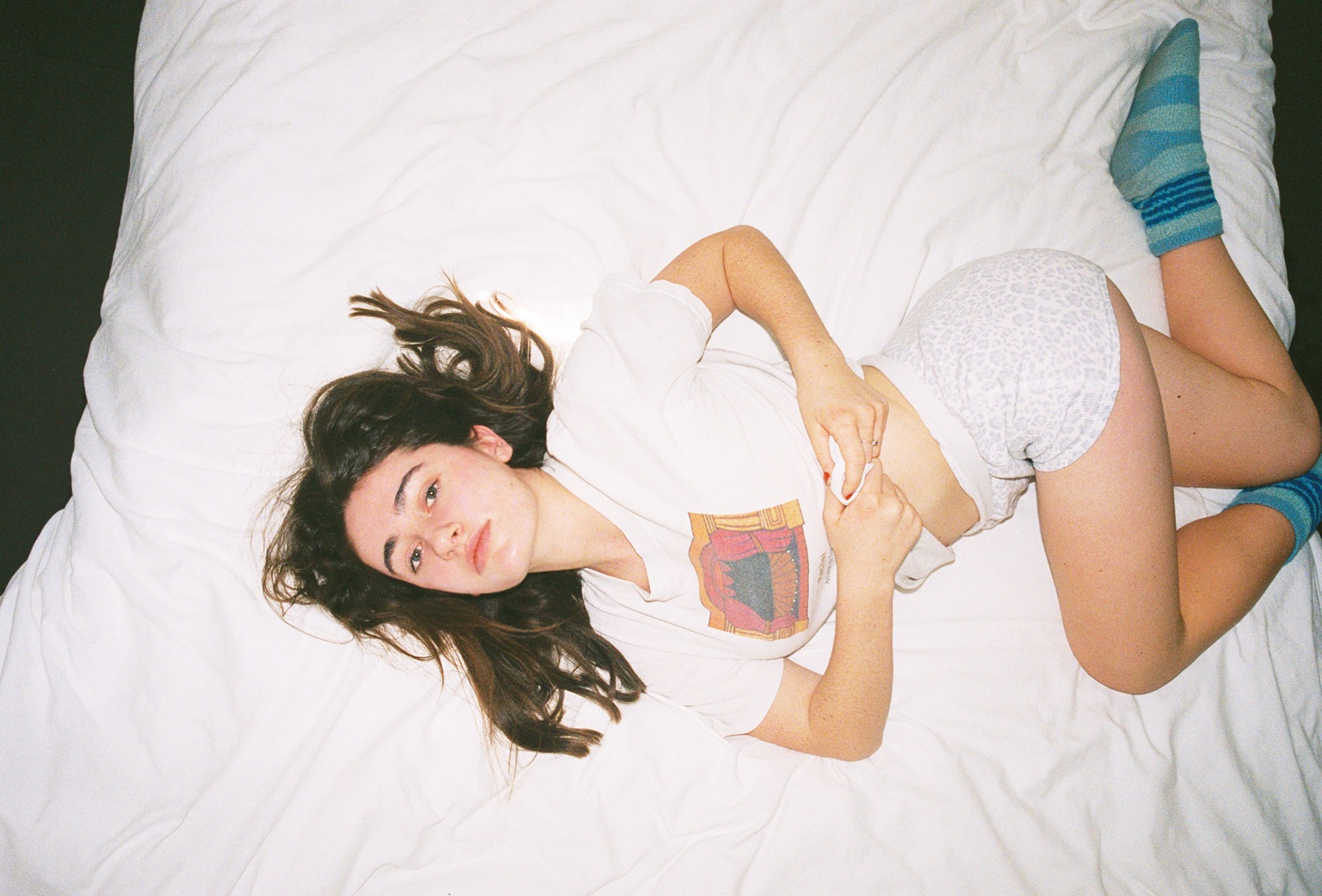 rachel sennott photographed by Morgan Maher posing in a t-shirt and shorts in bed