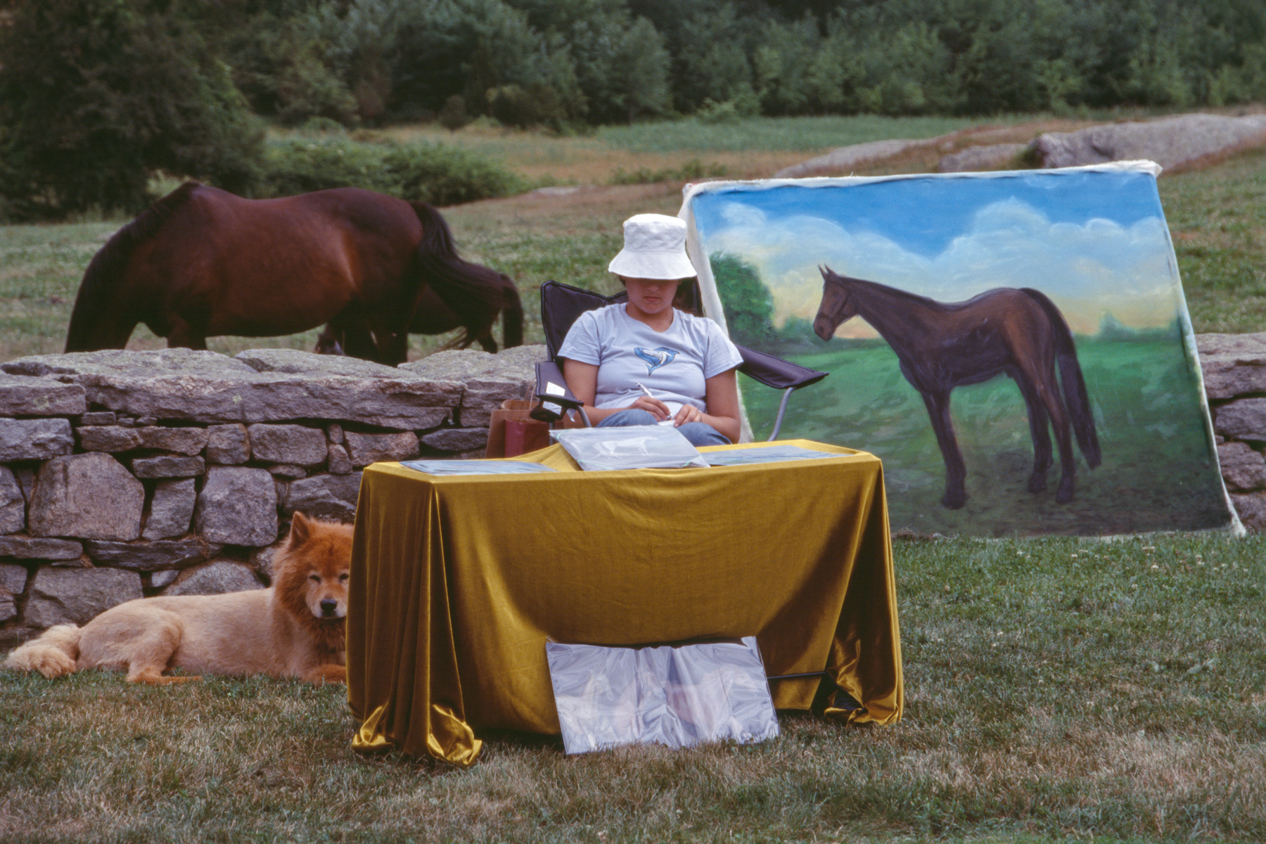 a woman sitting at a table covered in yellow velvet surrounded by a horse, a dog, and a painting of a horse