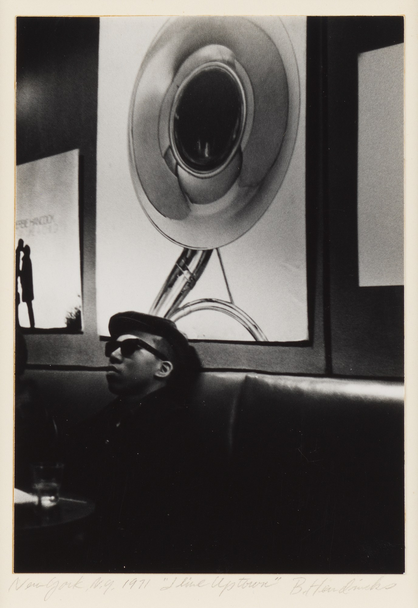 a young man sitting in a bar wearing a black hat and sunglasses