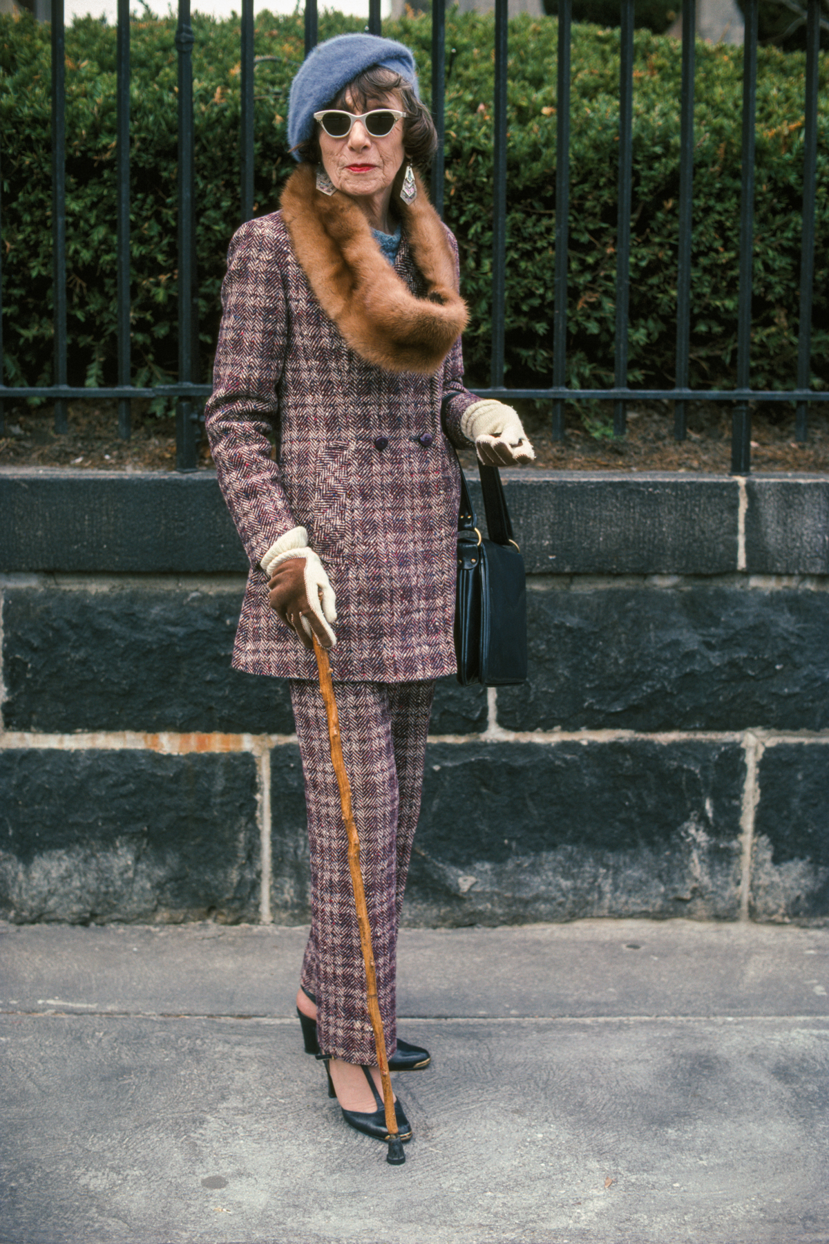 an older woman in a plaid suit with a cane