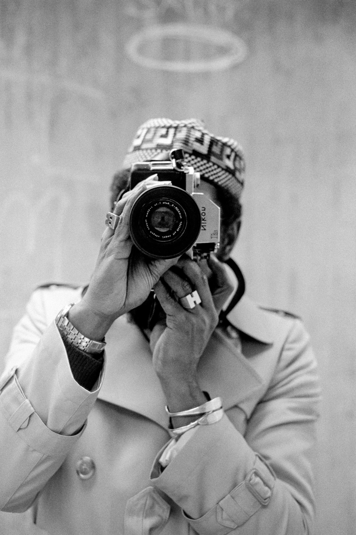 Barkley L Hendricks taking a self portrait while wearing a trench coat