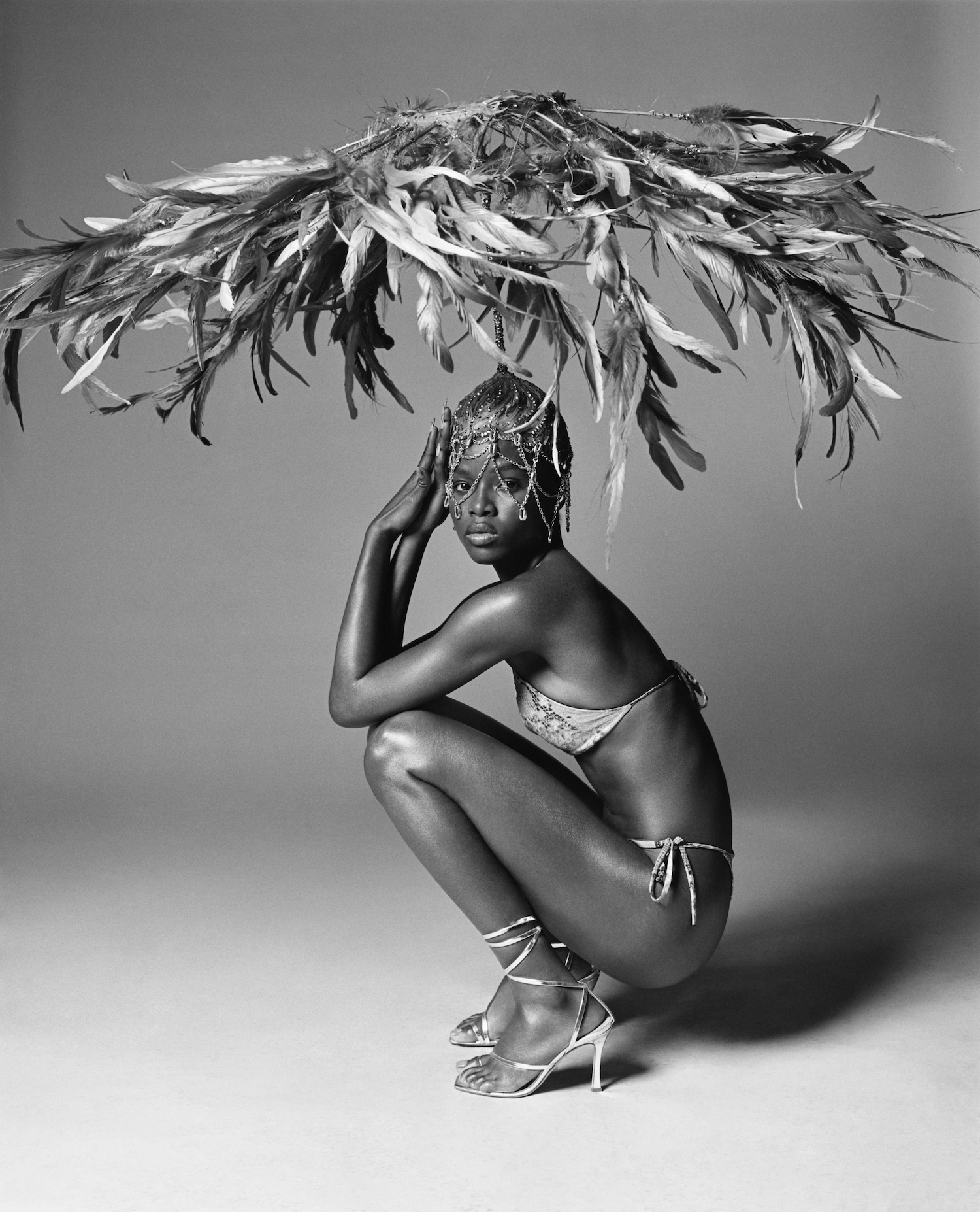 Black-and-white photo of a model with a towering head dress wearing Theophilio