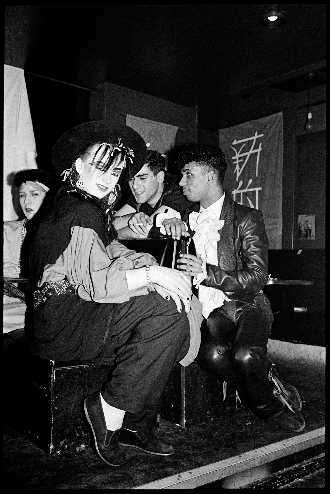 boy george posing in a hat with friends at the wall