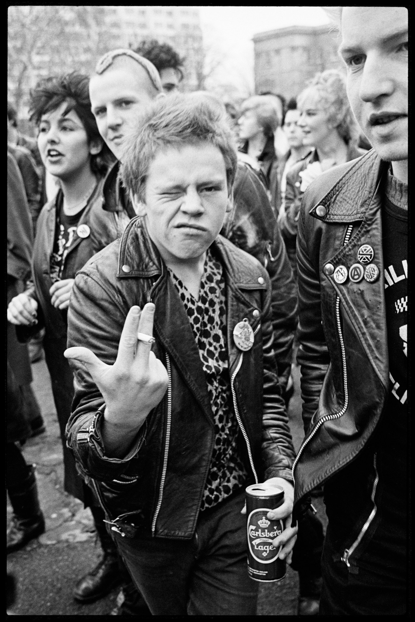 punk guy smoking a cigarette and holding a carlsberg at the sid vicious memorial march 1980