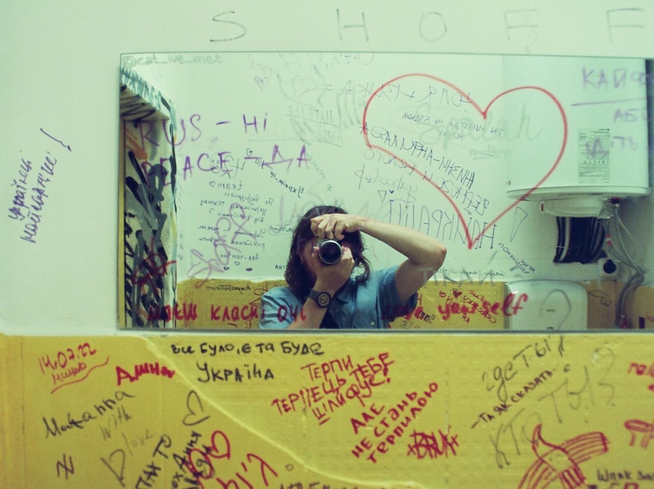 a girl taking a photo in a mirror with marker graffiti and a drawn heart