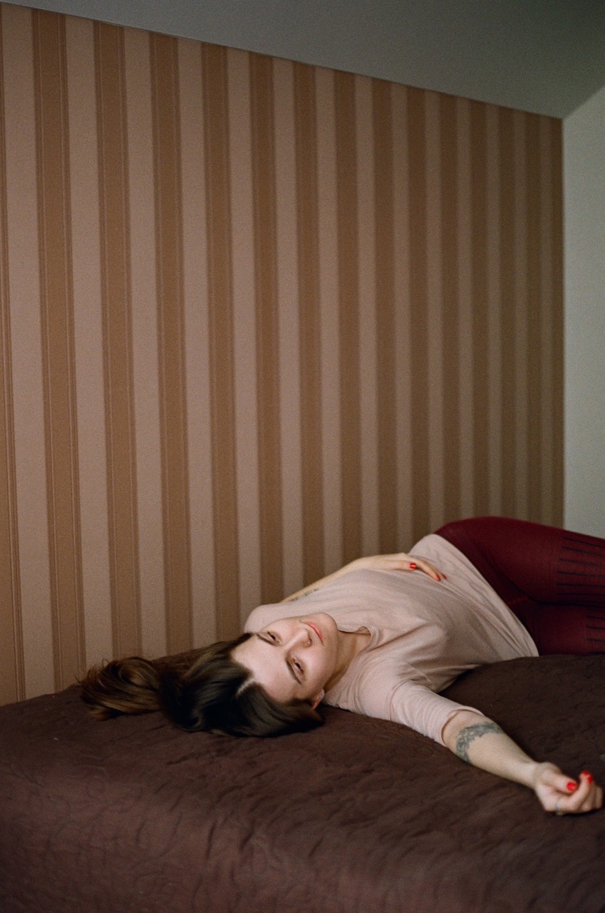 a girl lying on a bed with her hand spread out in front of striped wallpaper