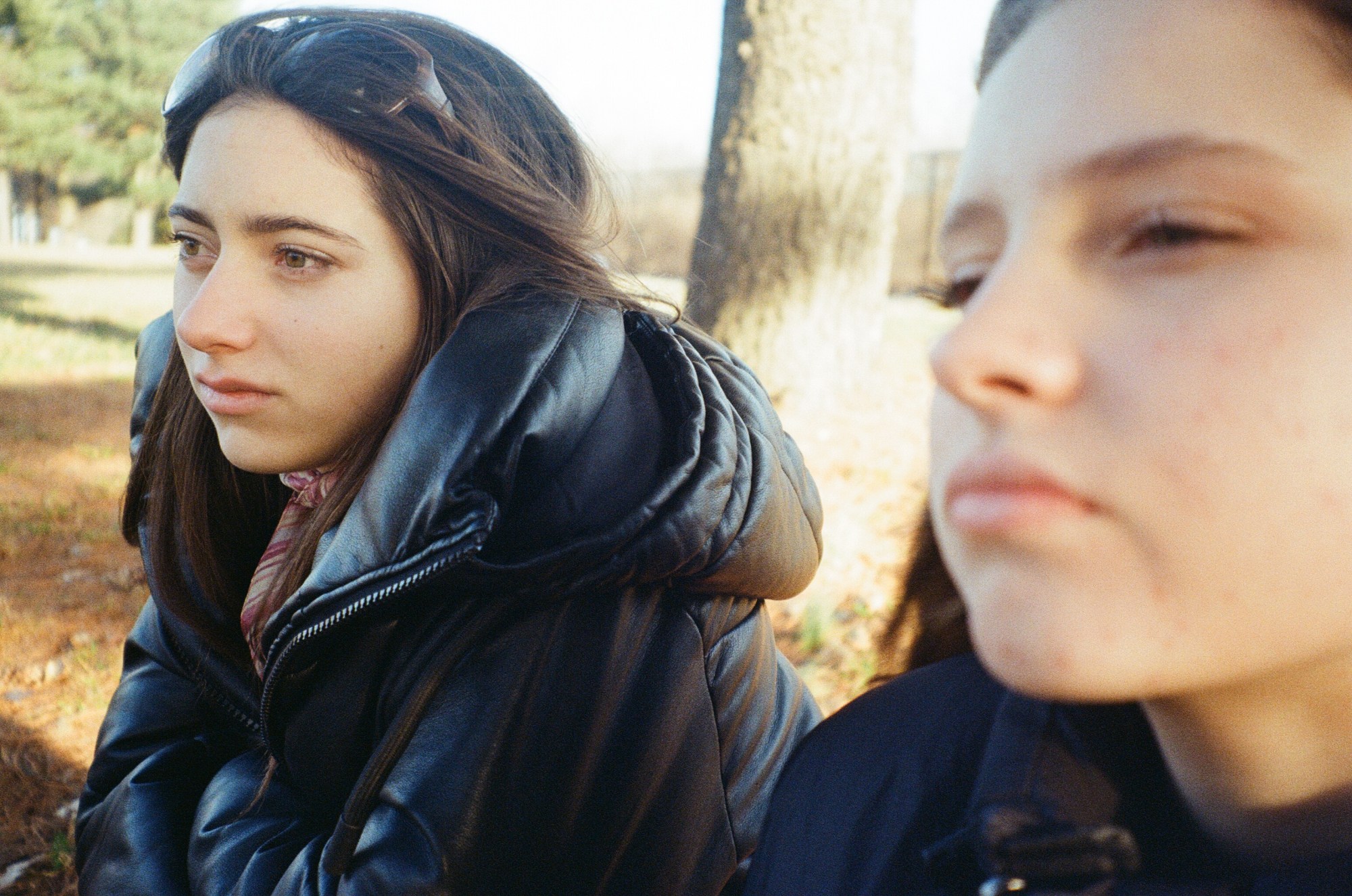 two young girls in puffer jackets sitting outside