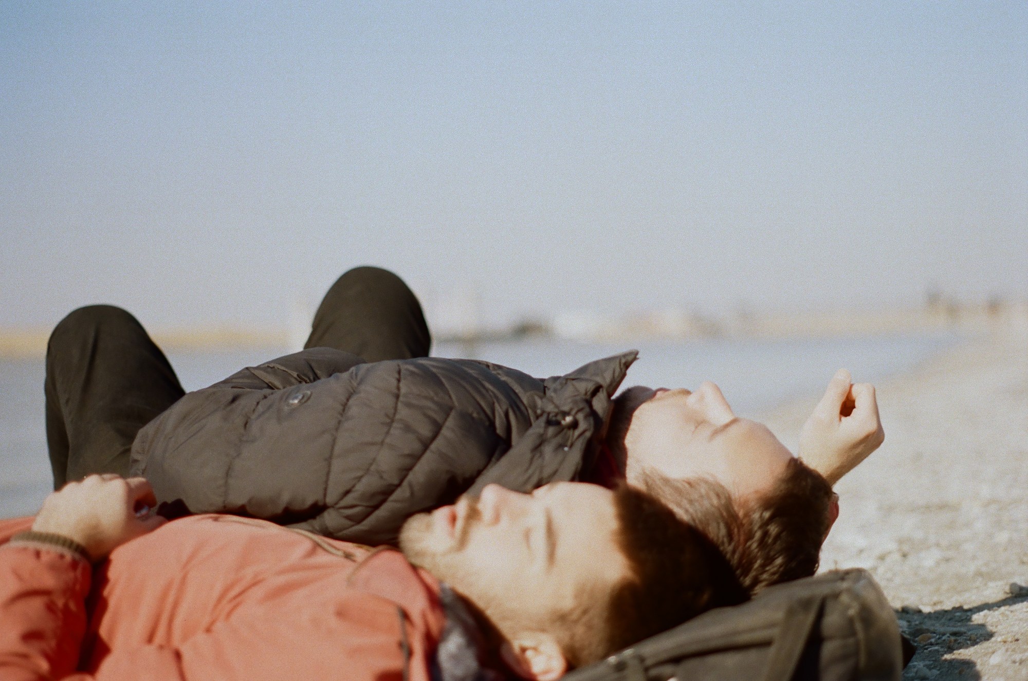 two young men lying on the ground in puffer jackets