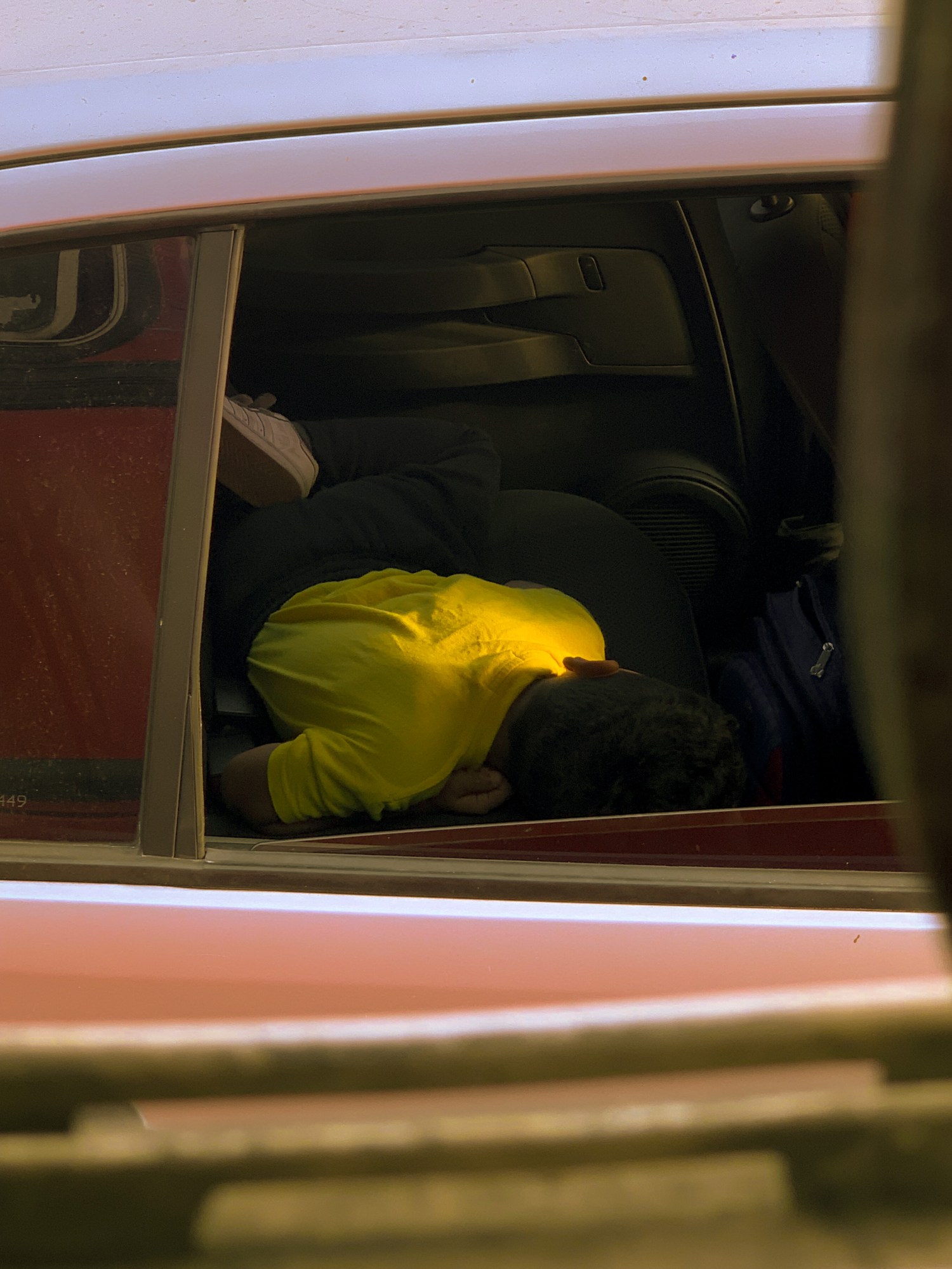 a young kid in a yellow shirt sleeping in a car