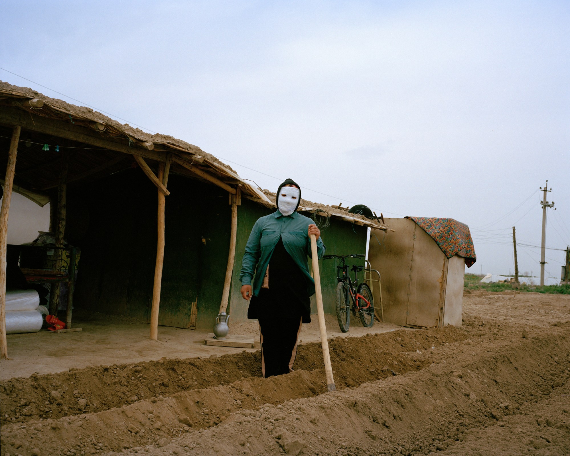 a masked woman tilling soil in uzbekistan