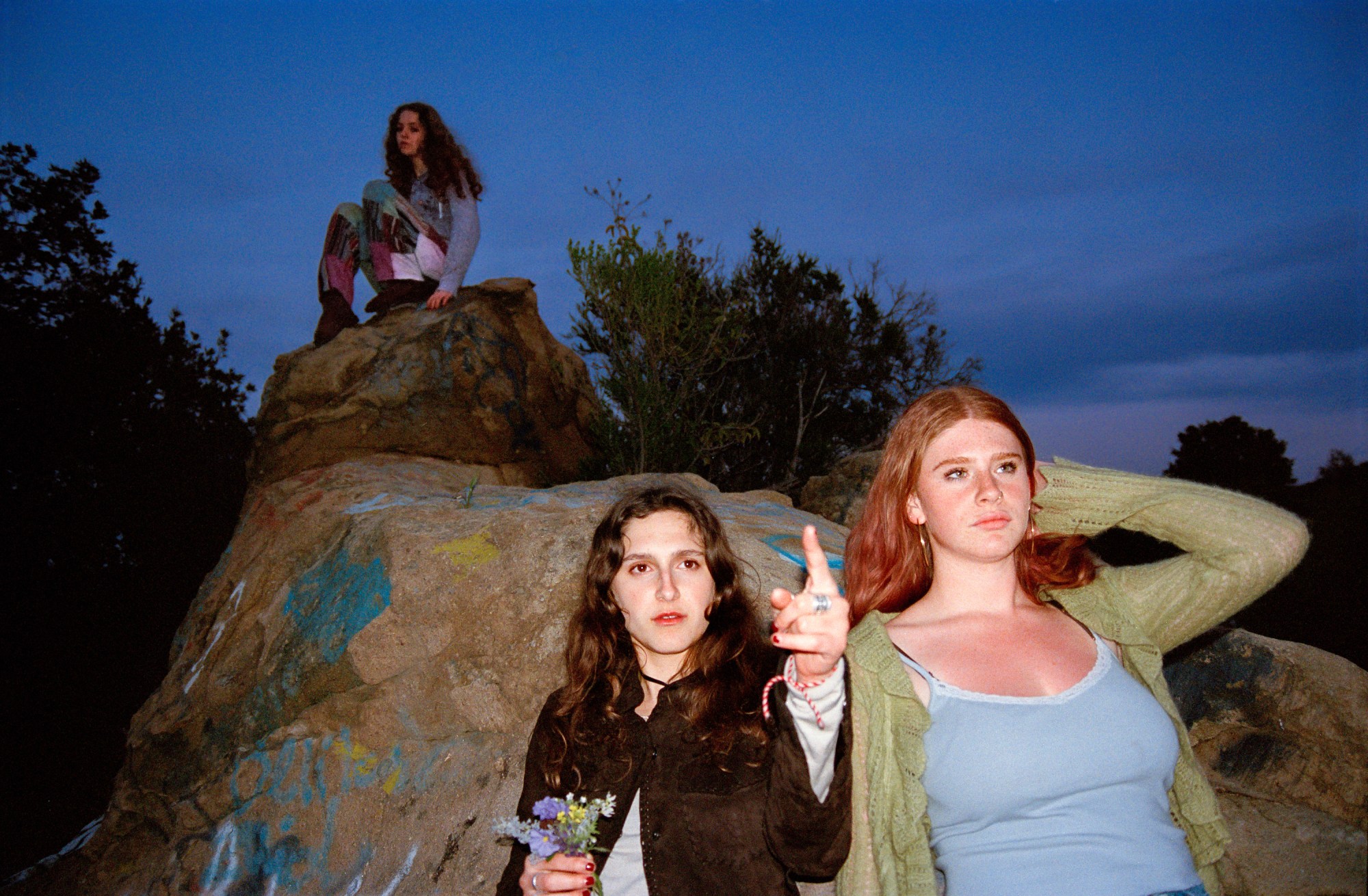 three young girls perched on a rock