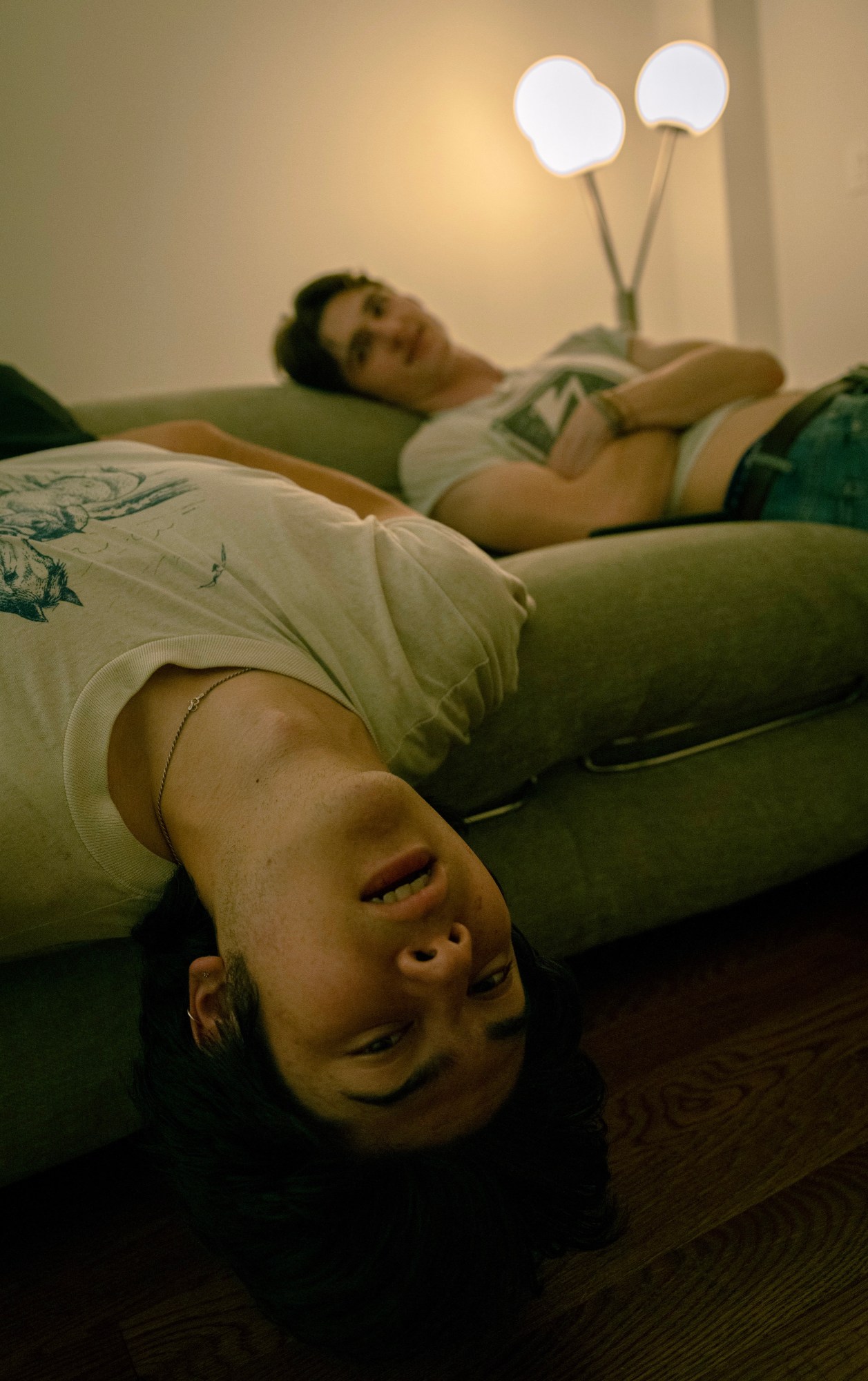 two young men on a couch, one sitting upside down