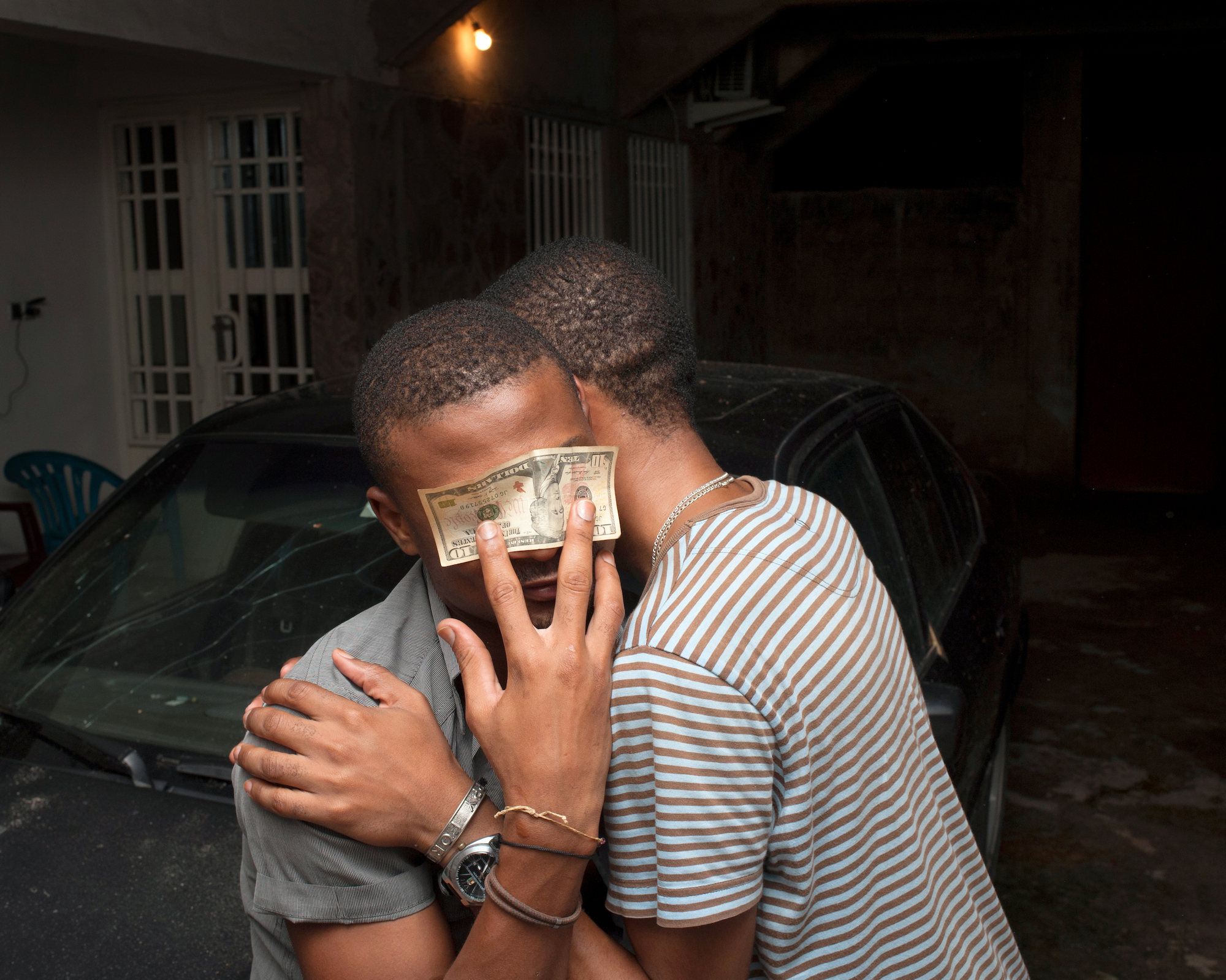 two lovers embracing as one covers his eyes with a ten dollar bill