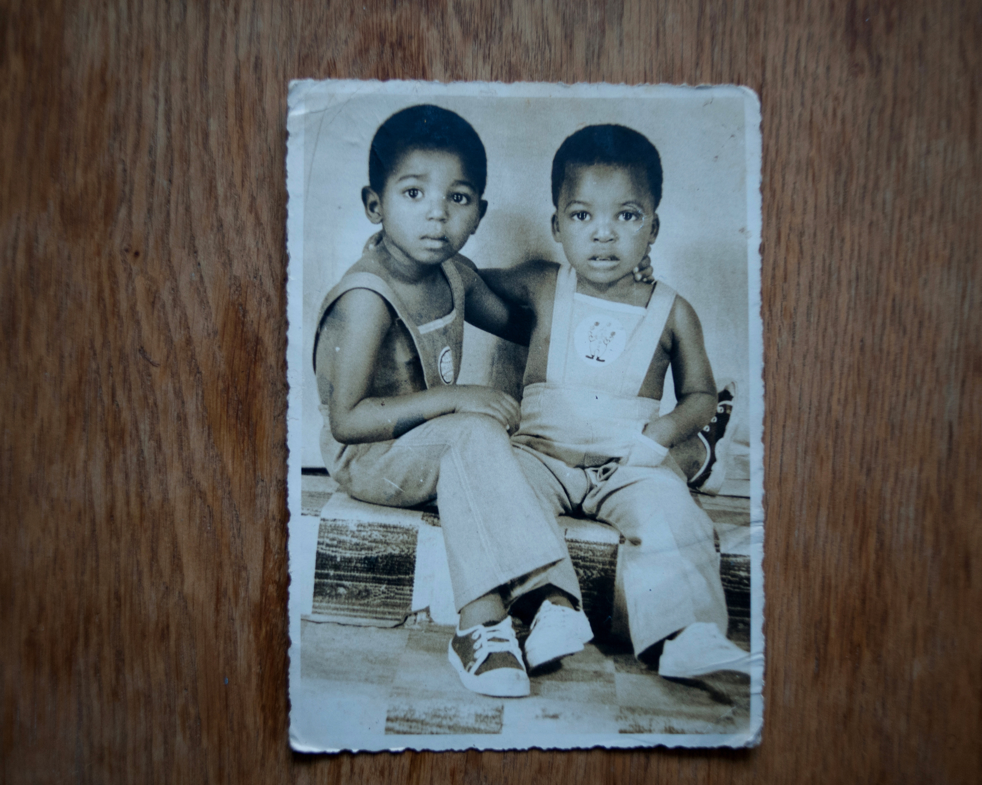 a sepia picture of two little boys in overalls