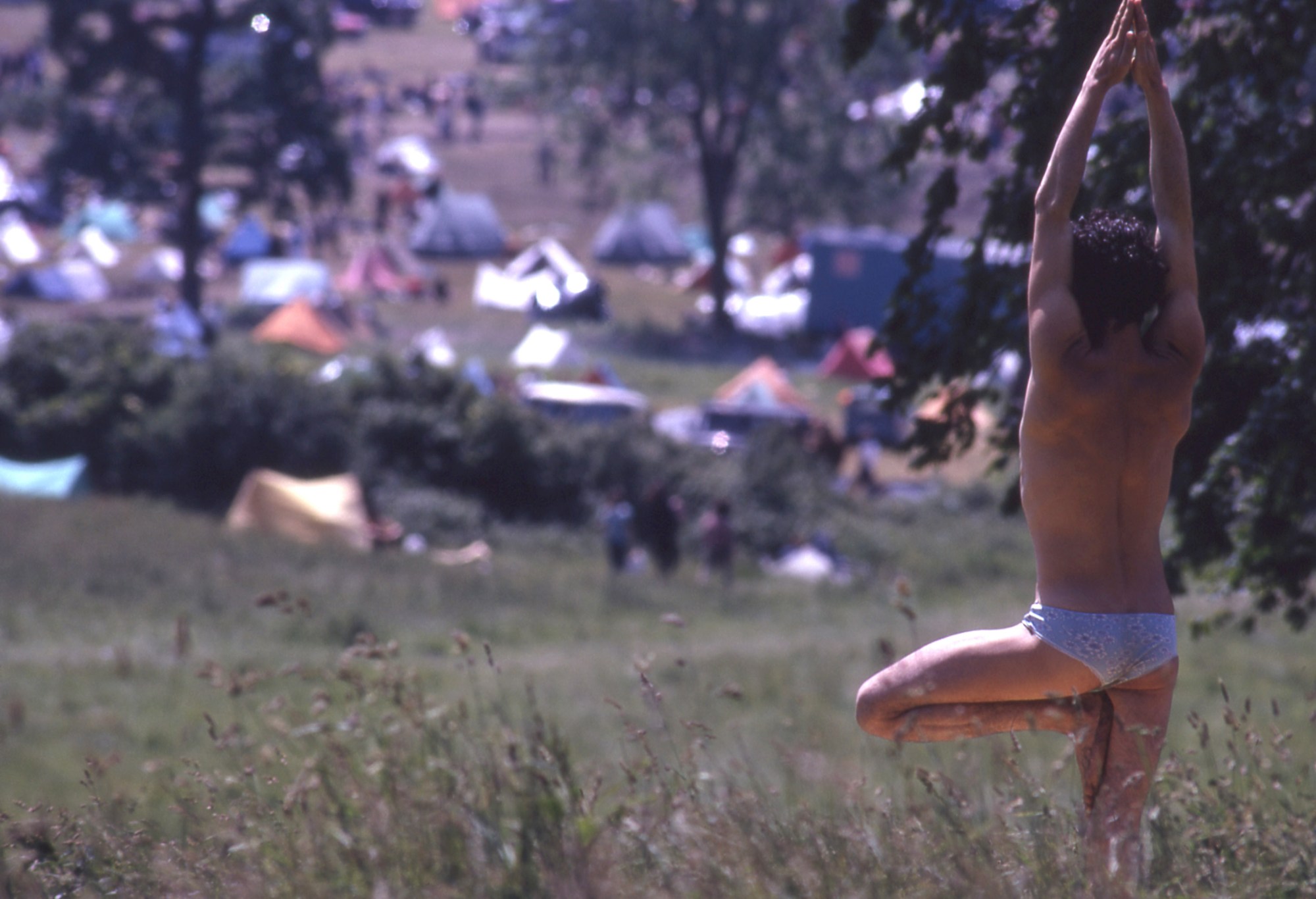 a man doing yoga in briefs in an open field at glastonbury music festival 1971