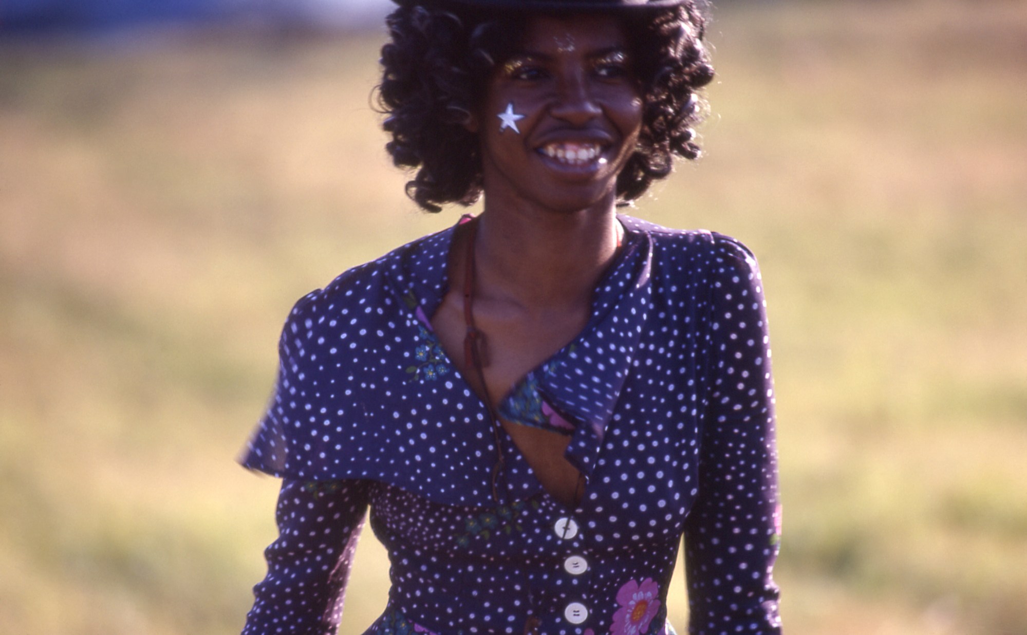 a girl in a blue polka dot top with a star and glitter makeup at glastonbury festival