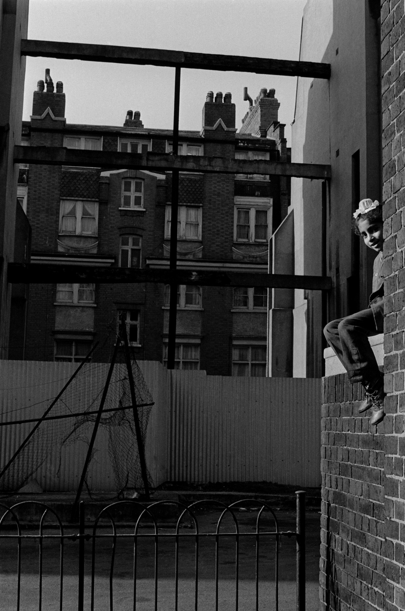 black and white photo of a young child sitting on the ledge of a building