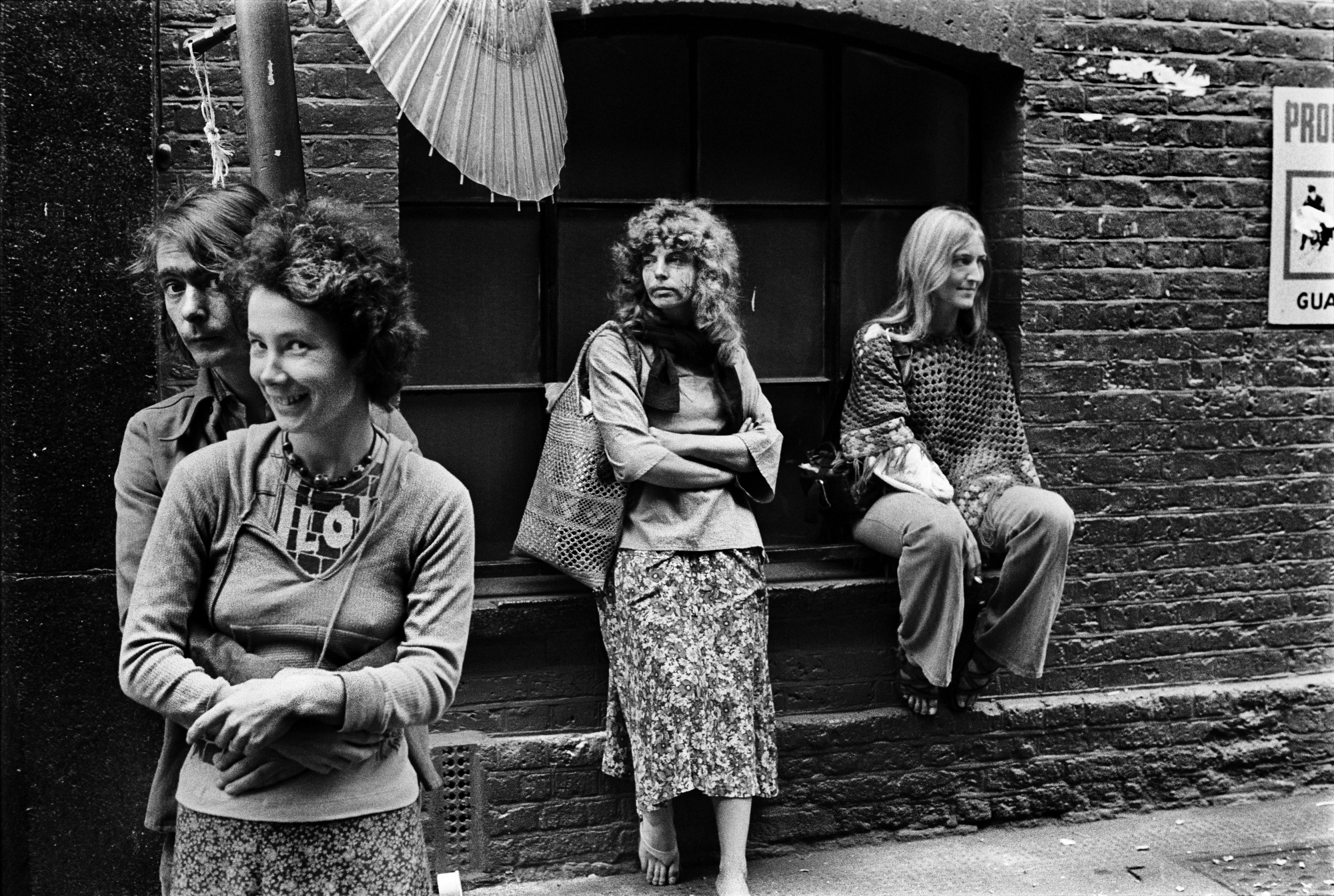 a couple embraces each other in the foreground while two models perch on a windowsill in the background