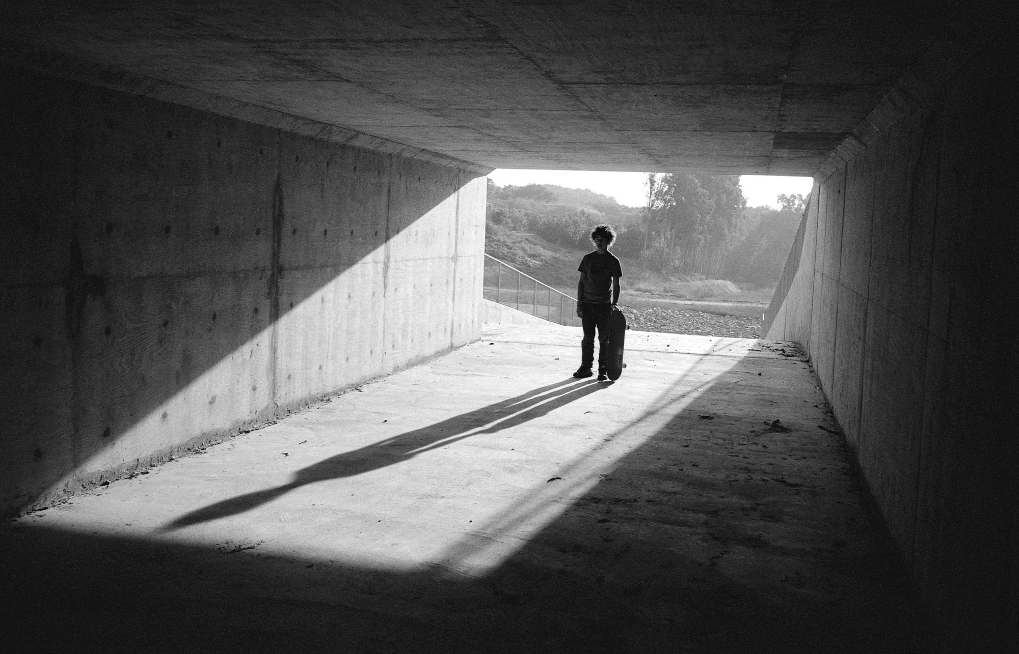 a silhouette of a young skater in a tunnel