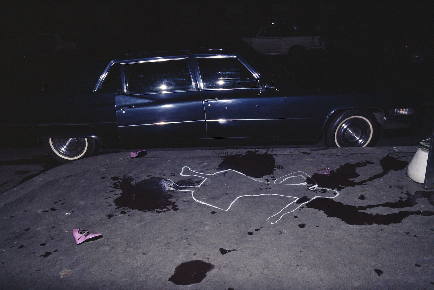 A black car next to a crime scene cut out of a blood splattered pavement